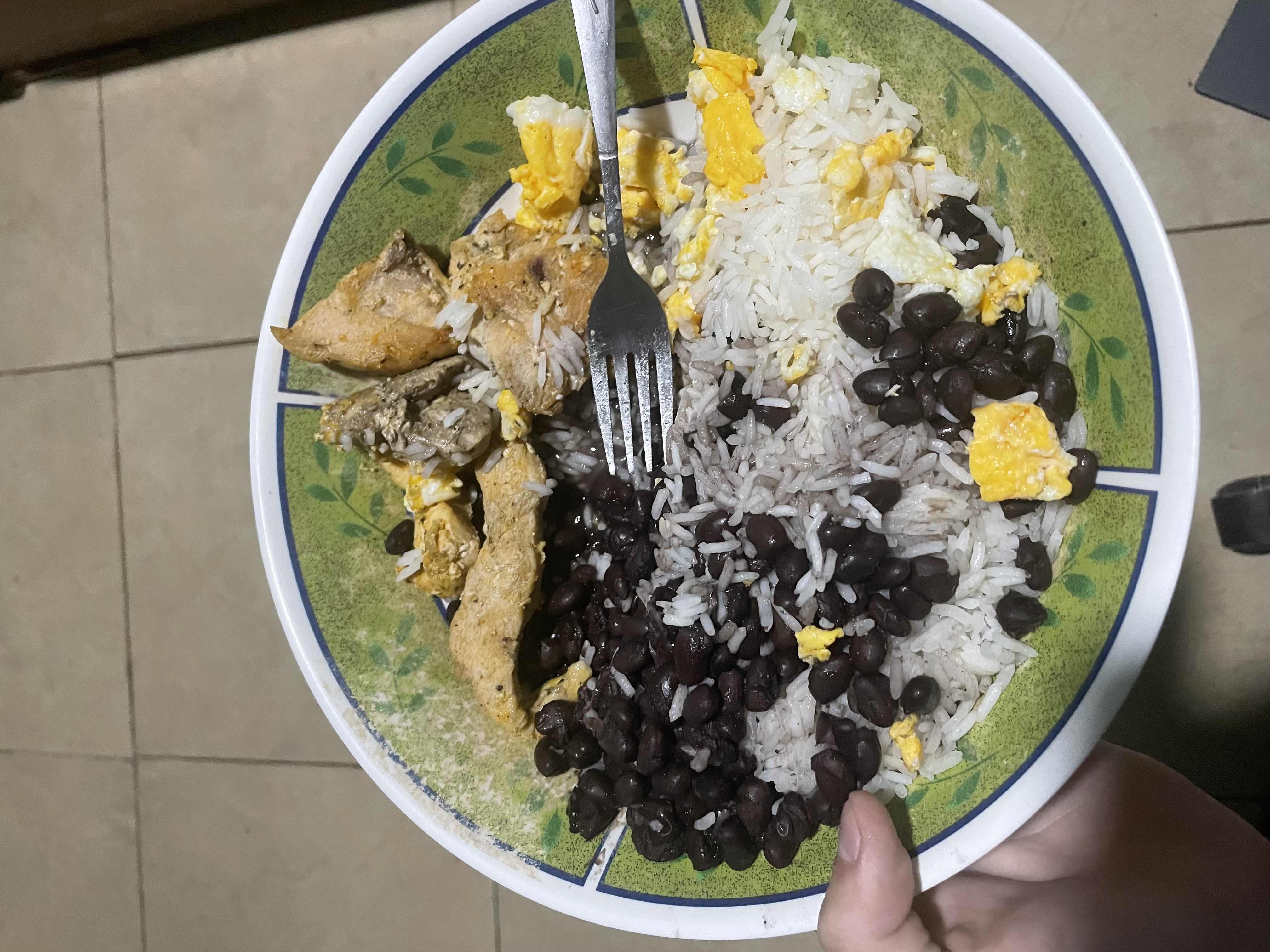 A balanced meal consisting of rice, black beans, chicken, and scrambled egg, providing a good mix of protein, carbohydrates, and fats.