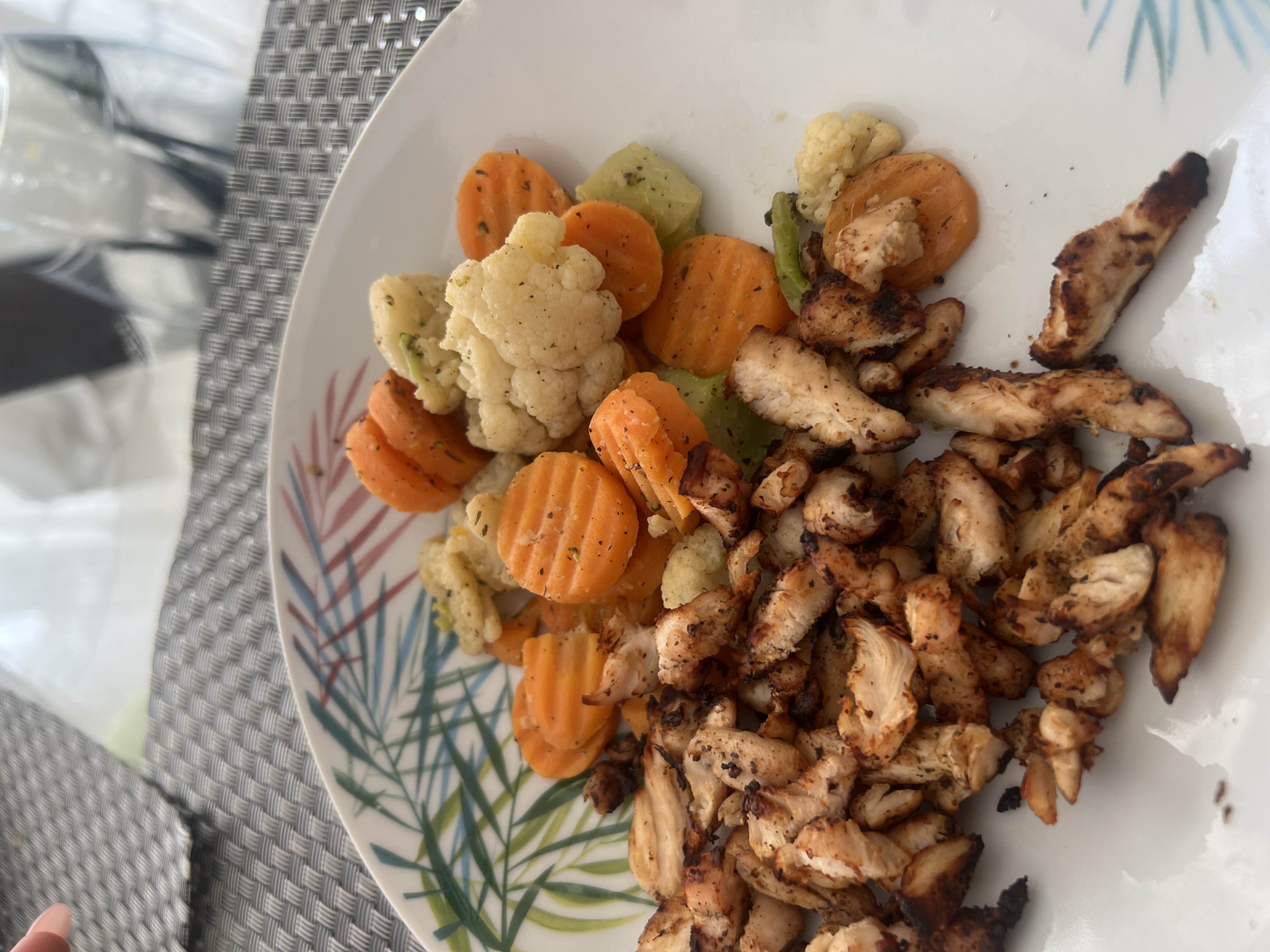 A healthy meal consisting of grilled chicken and a mix of steamed vegetables including carrots, cauliflower, and broccoli.