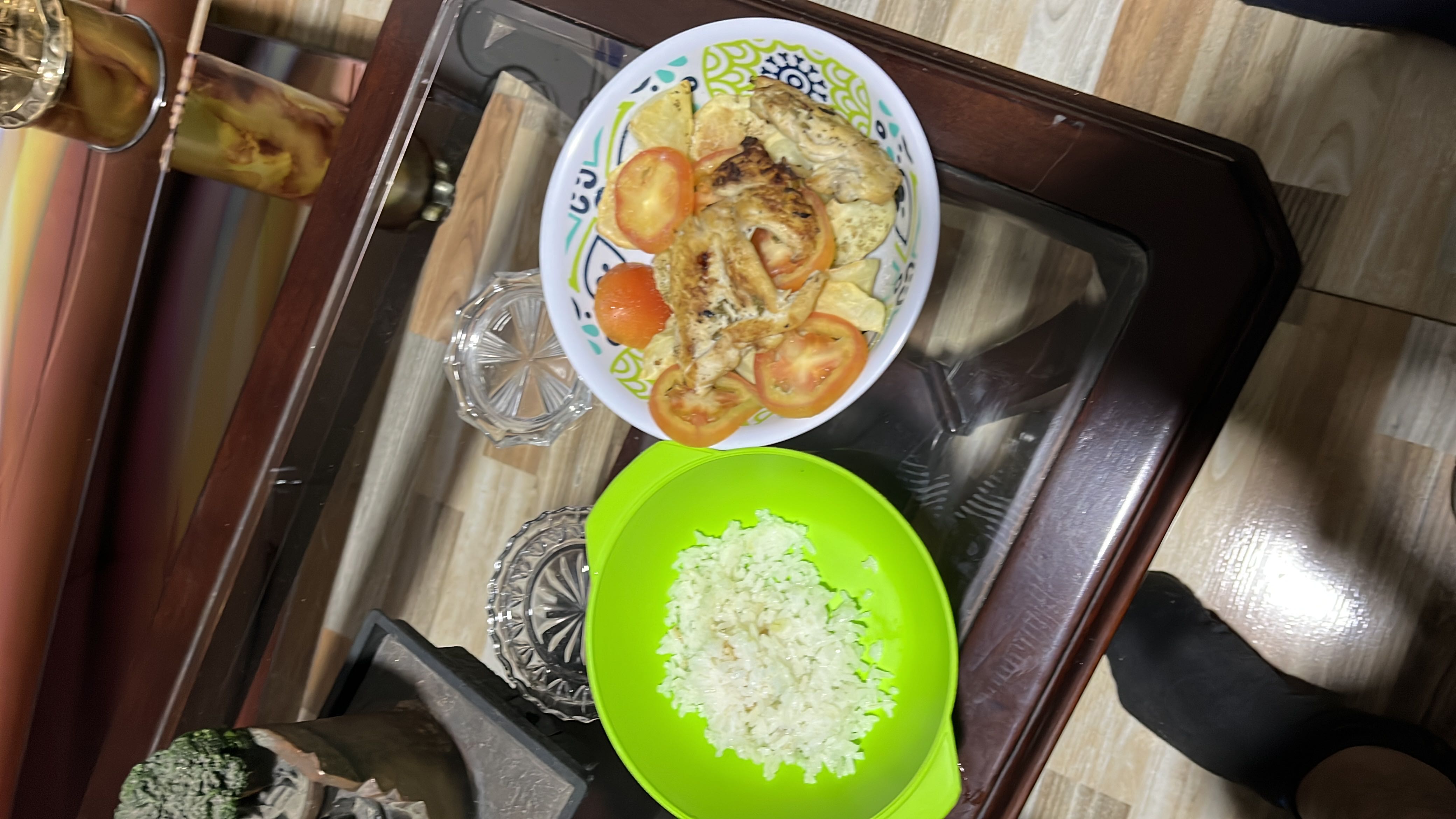 A balanced meal consisting of grilled chicken, rice, fresh tomatoes, and potato chips, providing a good mix of protein, carbohydrates, and fats.