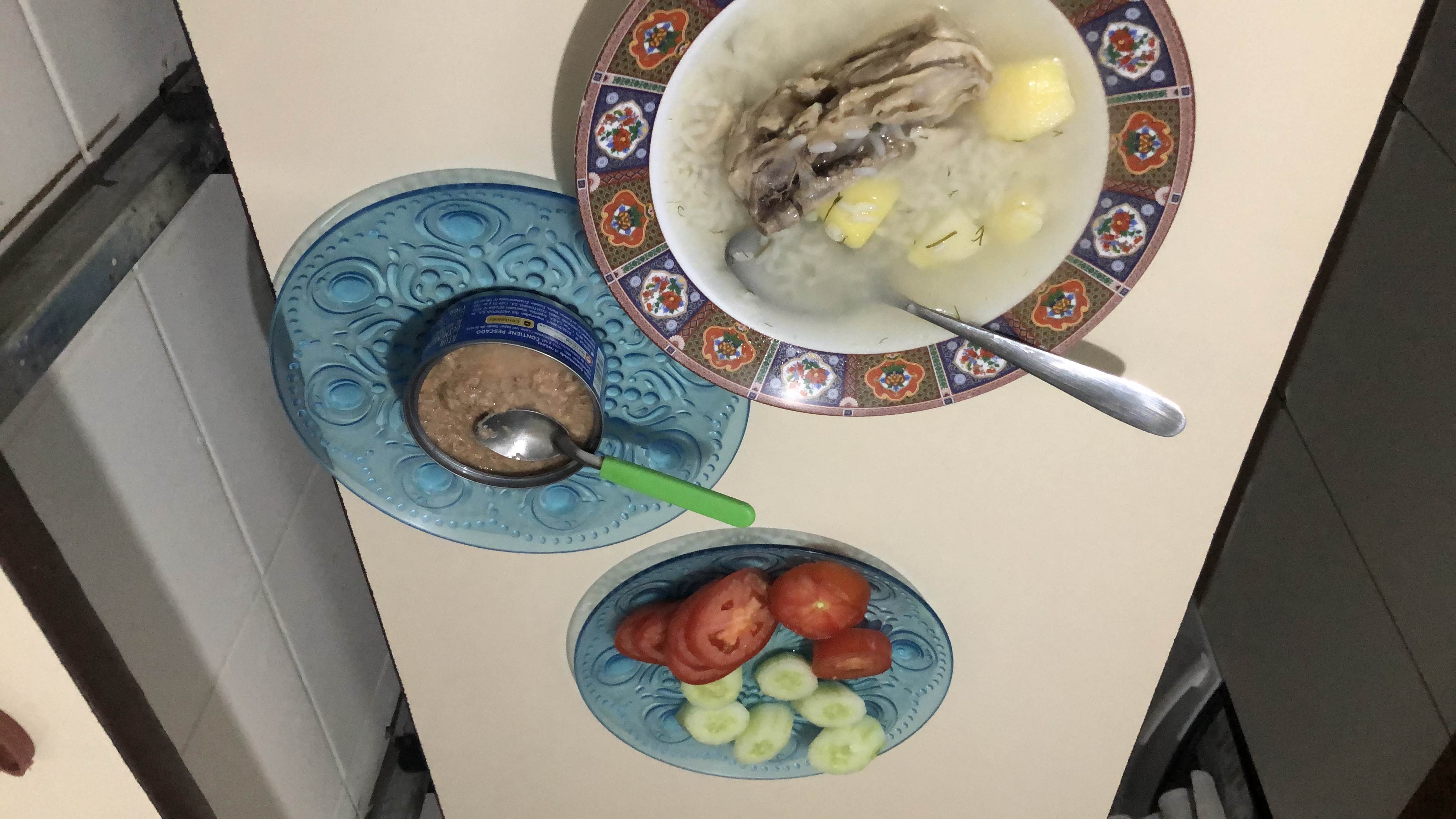 A balanced meal consisting of chicken soup with rice and potatoes, accompanied by fresh cucumber and tomato slices, and canned tuna.