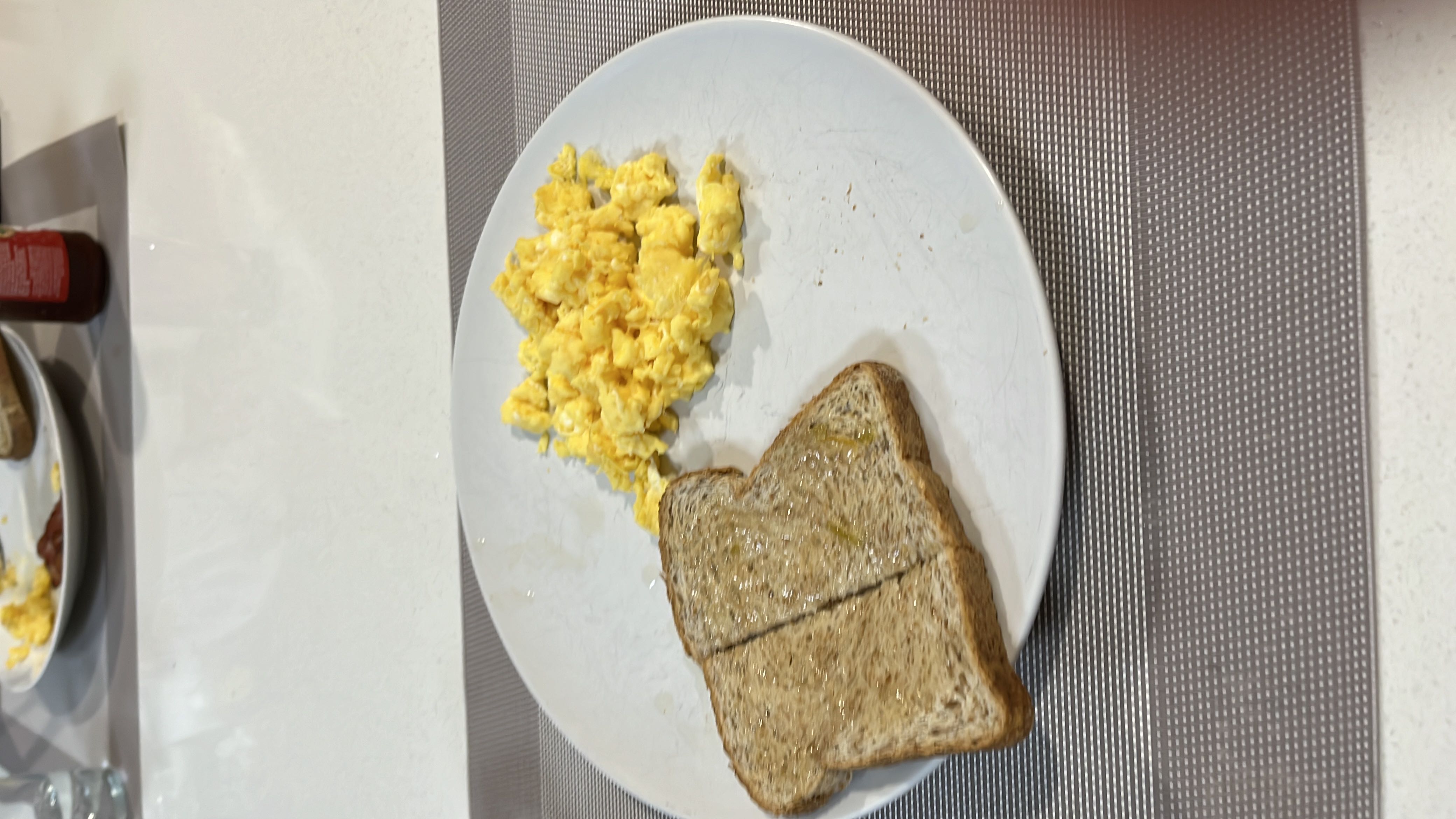 A breakfast plate containing scrambled eggs and whole wheat toast with butter, providing a balanced mix of protein, carbs, and fats.