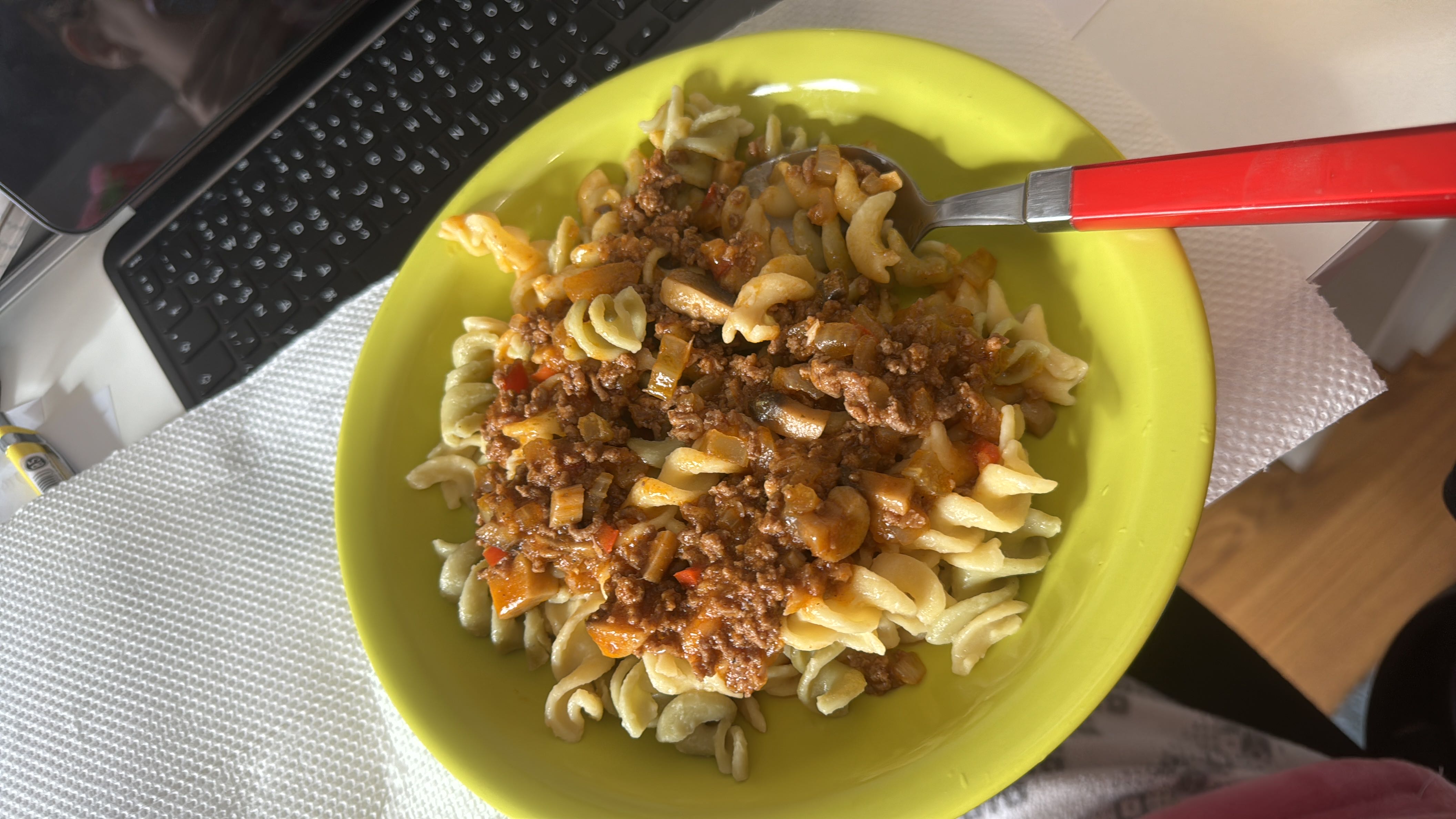 A plate of fusilli pasta with a ground beef and vegetable-based sauce, providing a balanced mix of protein, carbohydrates, and fats.