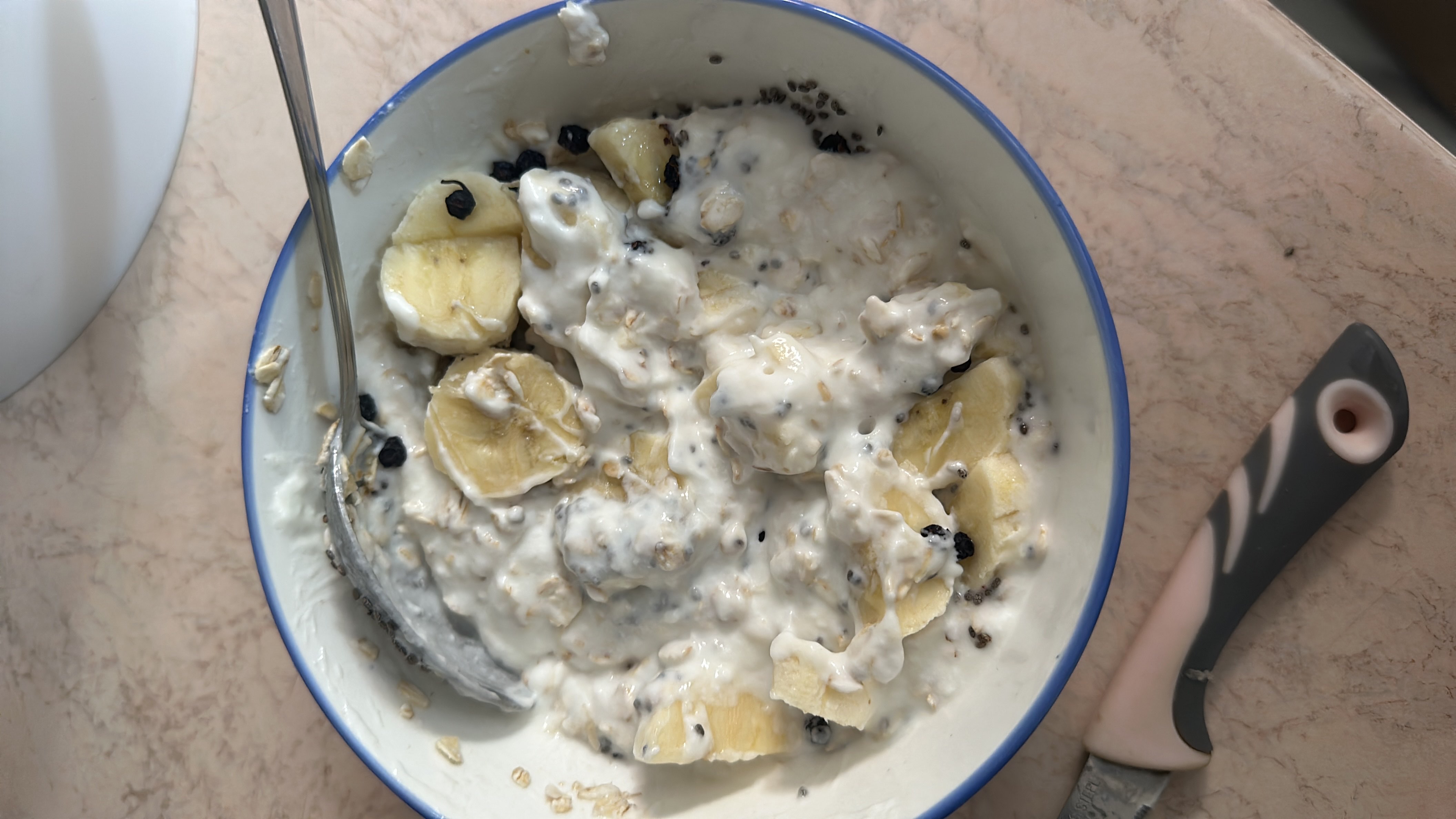A nutritious bowl of Greek yogurt mixed with oats, banana slices, blueberries, and chia seeds, providing a balanced mix of protein, carbs, and healthy fats.