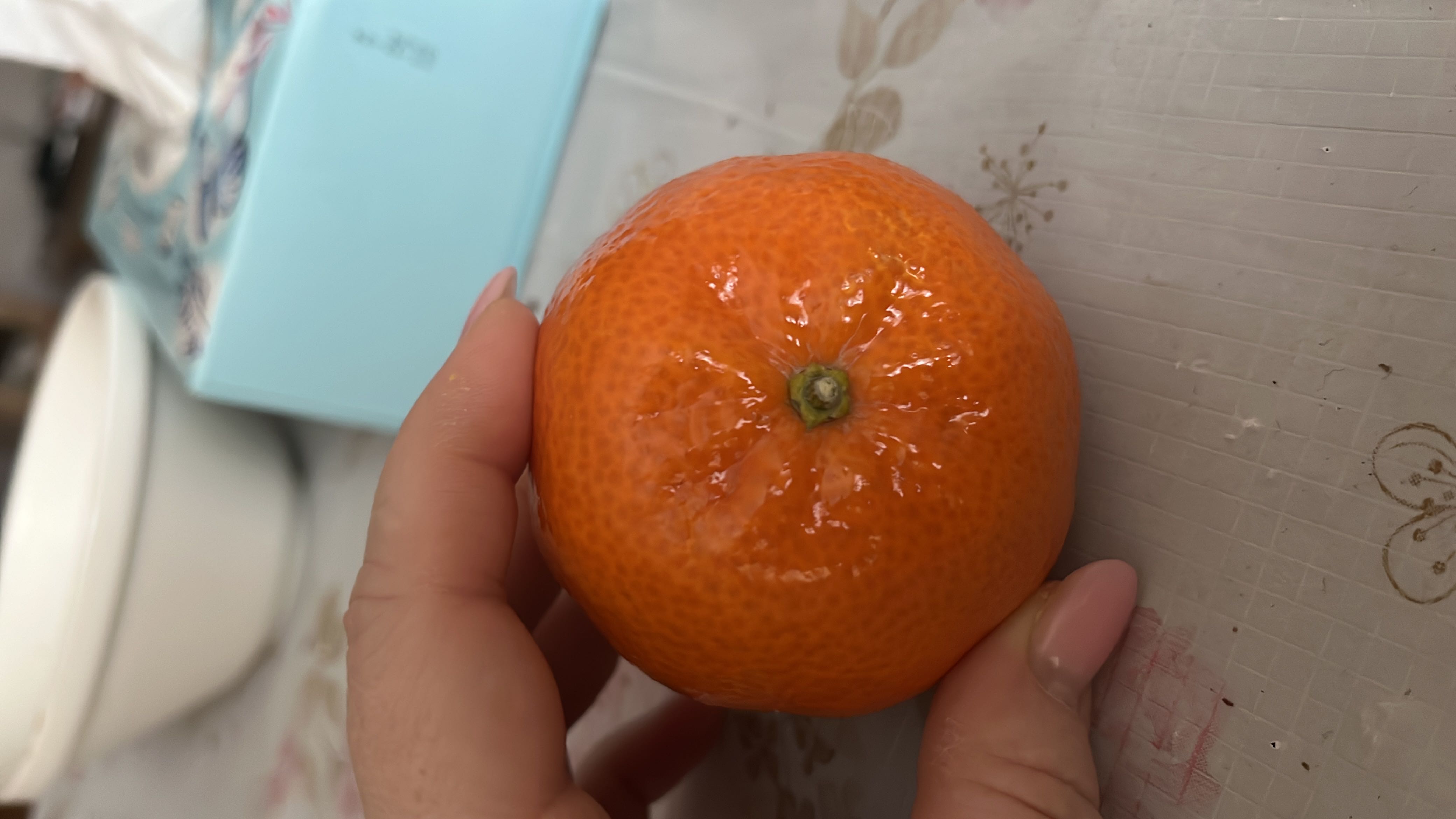 A fresh mandarin orange, rich in vitamin C and low in calories, making it a healthy snack option.