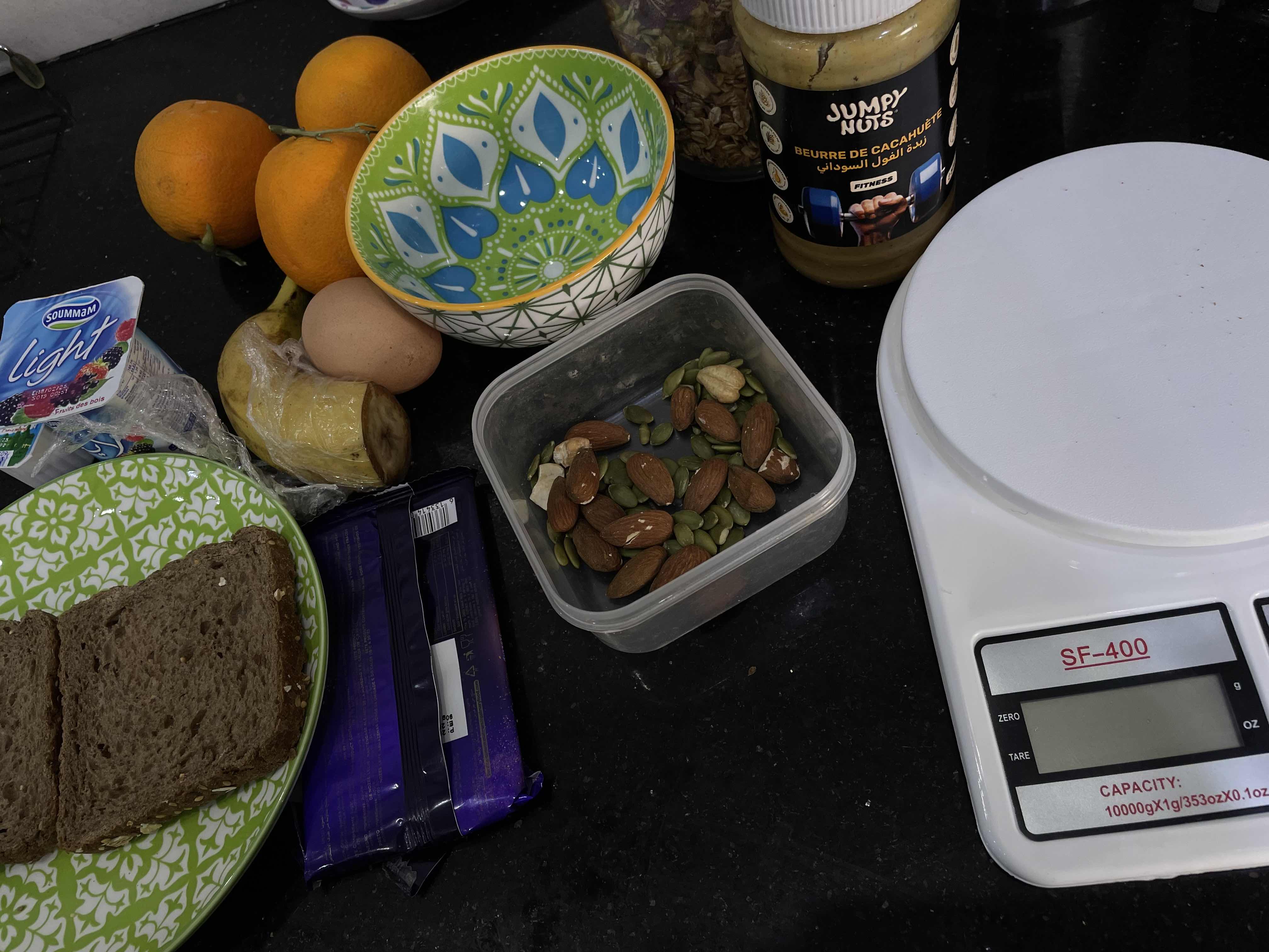 A balanced meal containing whole grain bread, nuts, peanut butter, fruits, and dairy, providing a good mix of protein, healthy fats, and carbohydrates.