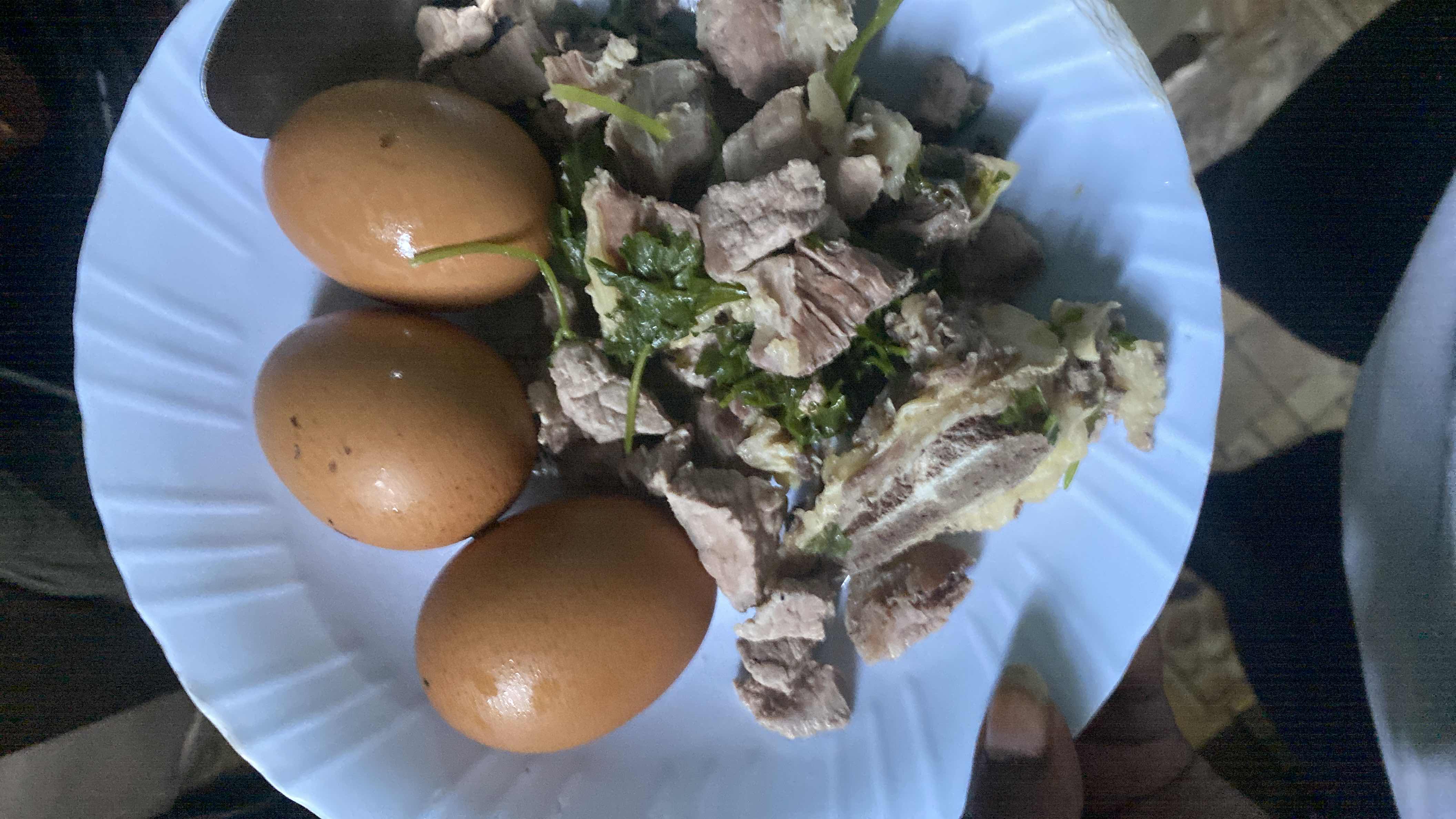 A high-protein meal consisting of boiled eggs, cooked meat, and fresh herbs, providing essential nutrients with minimal carbohydrates.