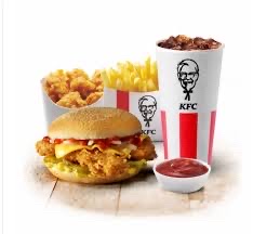 A fast-food meal consisting of a fried chicken burger without sauce and cheese, french fries, soft drink, and additional fried chicken pieces.