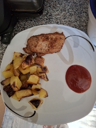 A balanced meal consisting of grilled chicken breast, roasted potatoes, and ketchup, providing a good mix of protein, carbohydrates, and fats.
