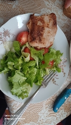 A plate containing grilled chicken, fresh lettuce, and tomato slices, offering a balanced and nutritious meal.