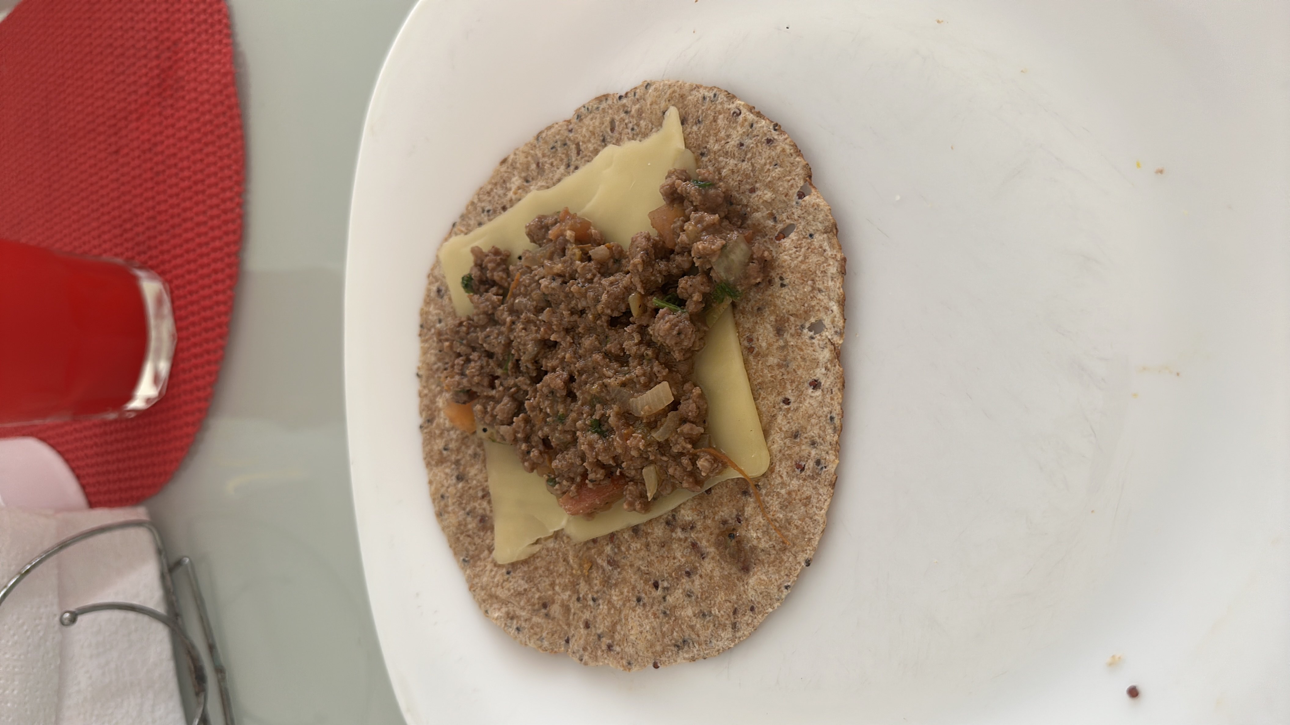 A whole wheat tortilla topped with a slice of cheese and seasoned ground beef, providing a balanced mix of protein, carbs, and fats.
