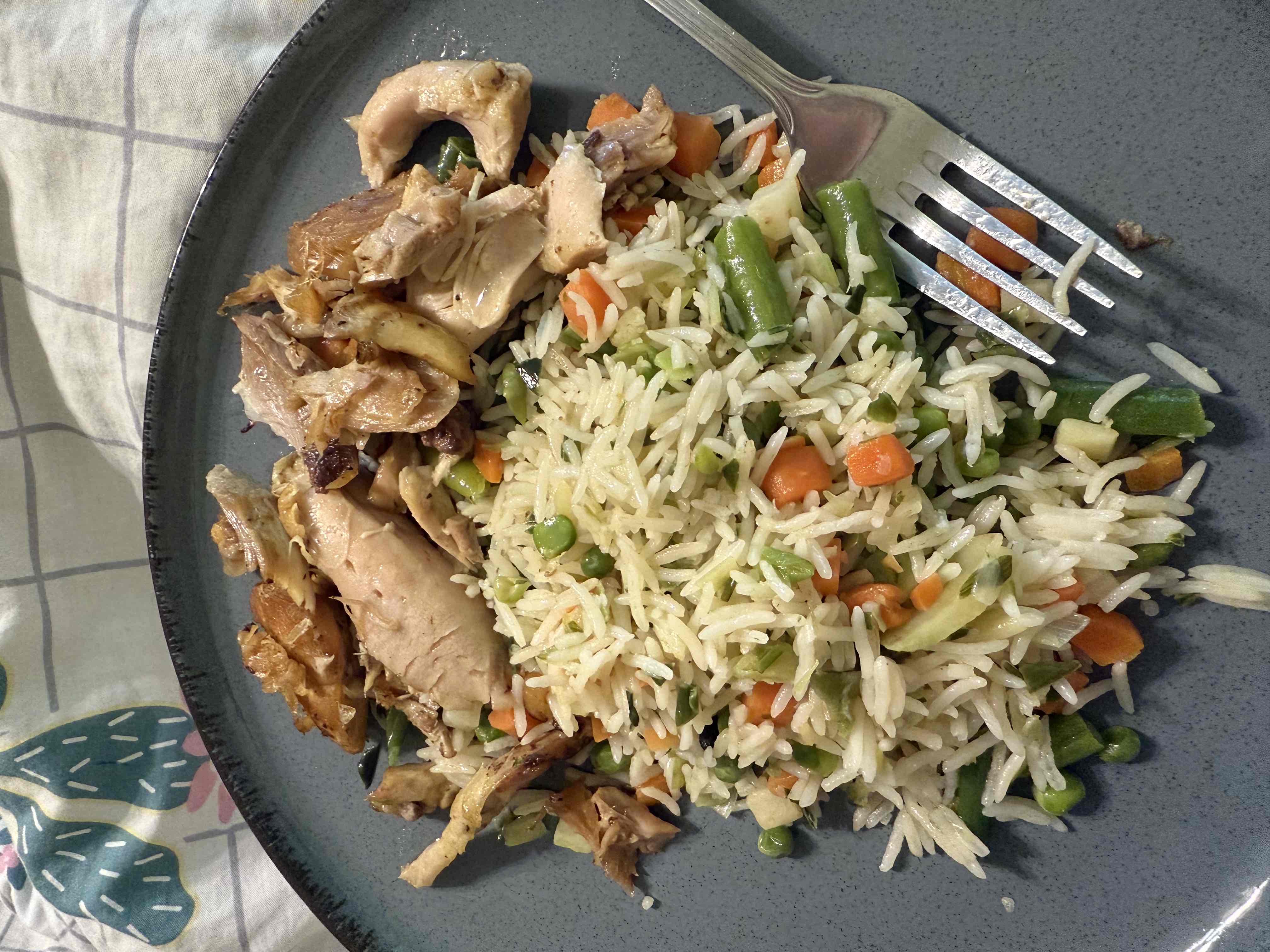 A plate of seasoned rice with mixed vegetables and roasted chicken, providing a balanced mix of protein, carbohydrates, and fats.