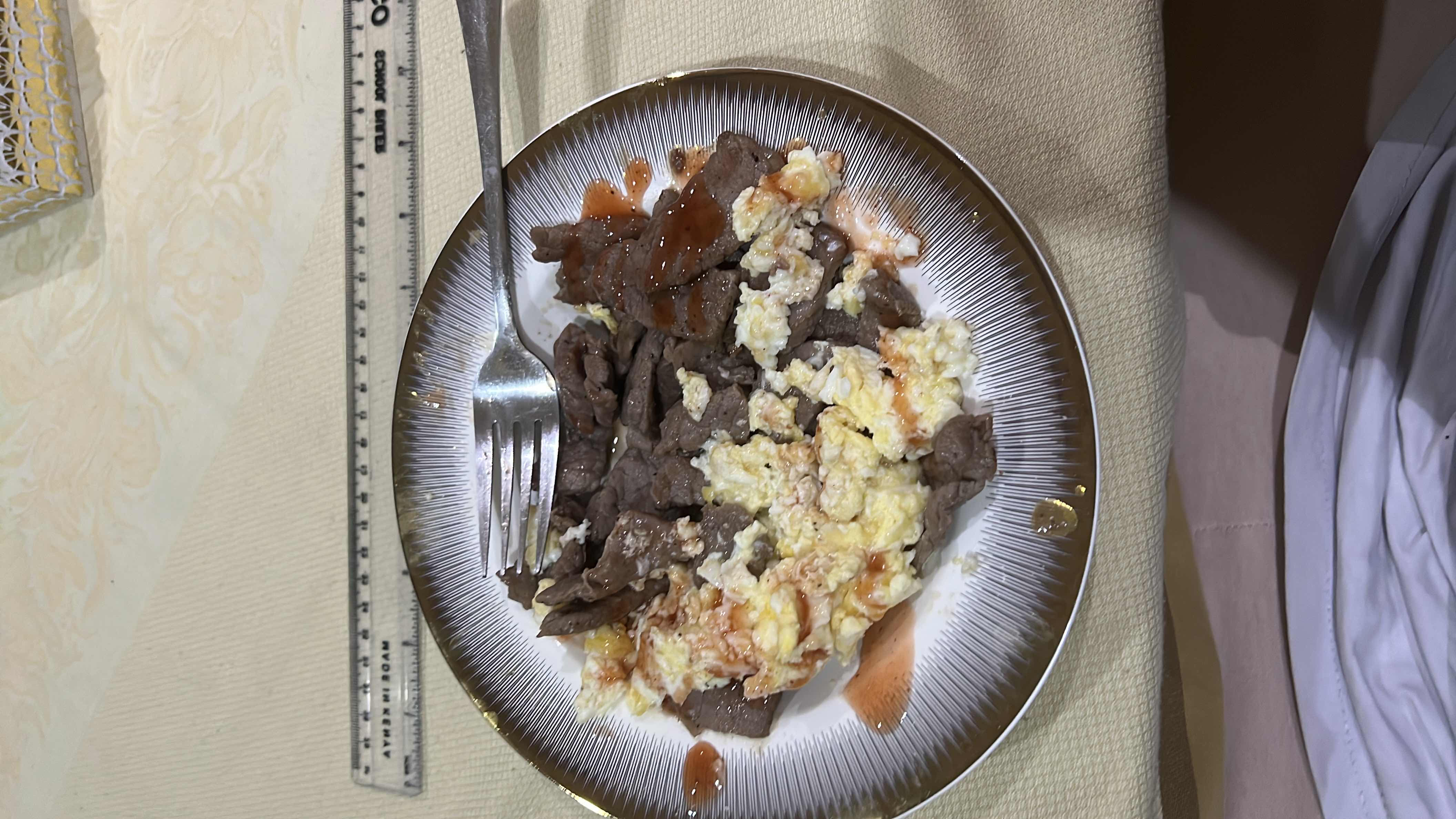 A protein-rich meal consisting of scrambled eggs and beef, topped with a sauce. It provides a balanced mix of protein and fats with minimal carbohydrates.