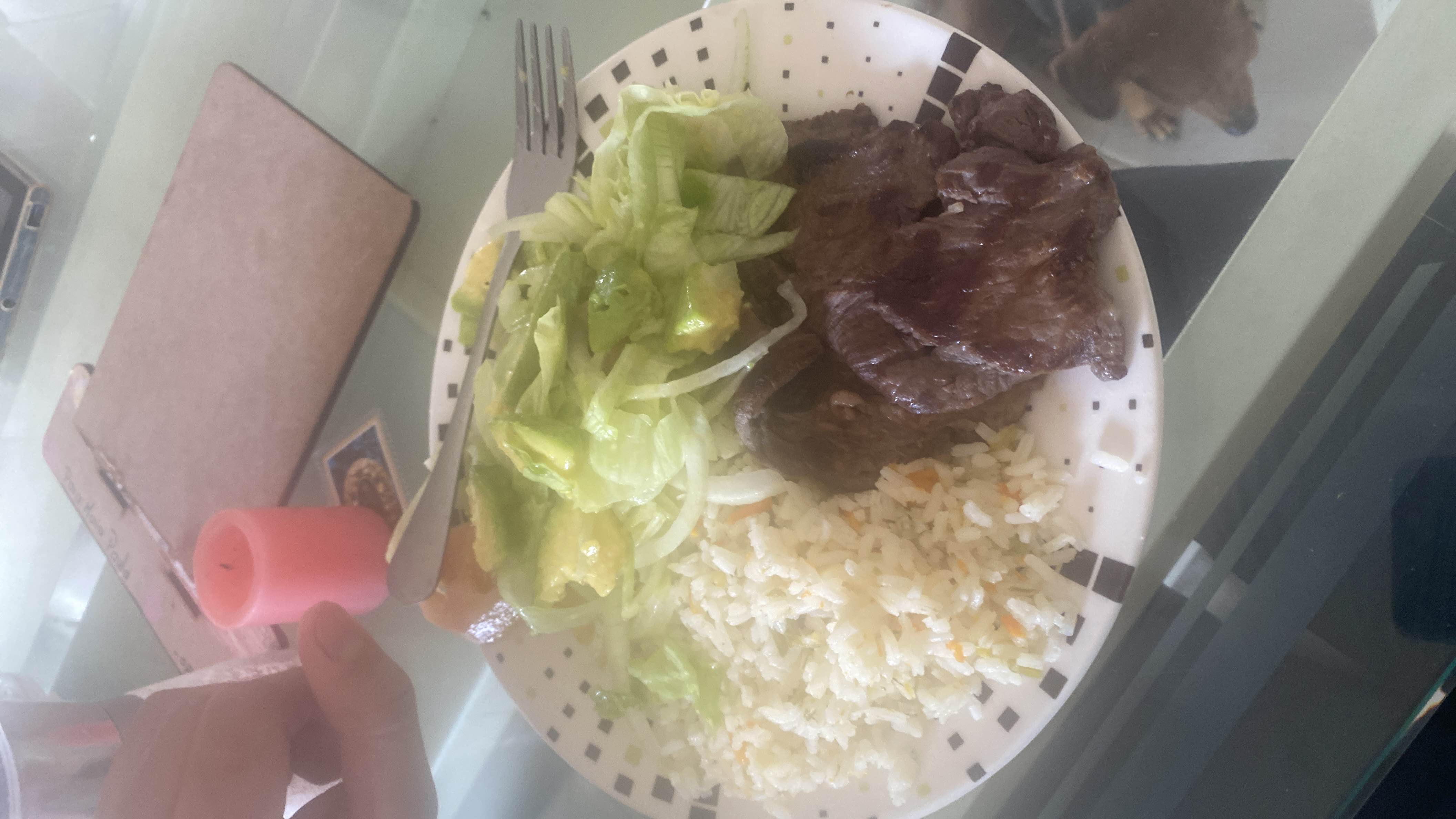 A balanced meal consisting of grilled beef, rice with vegetables, and a fresh lettuce and avocado salad.