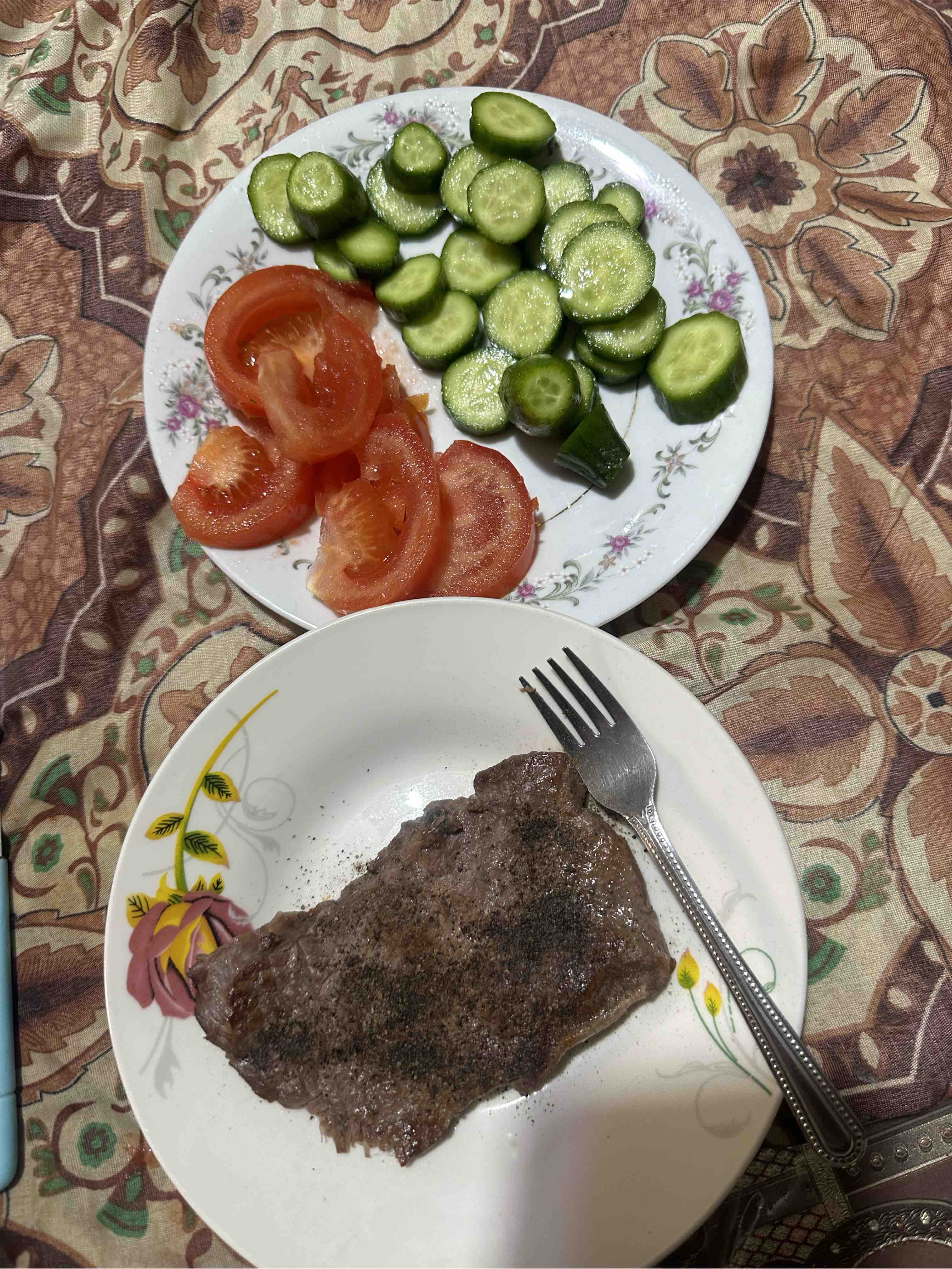 A balanced meal consisting of a seasoned beef steak with fresh cucumber and tomato slices, providing a good mix of protein, healthy fats, and fiber.
