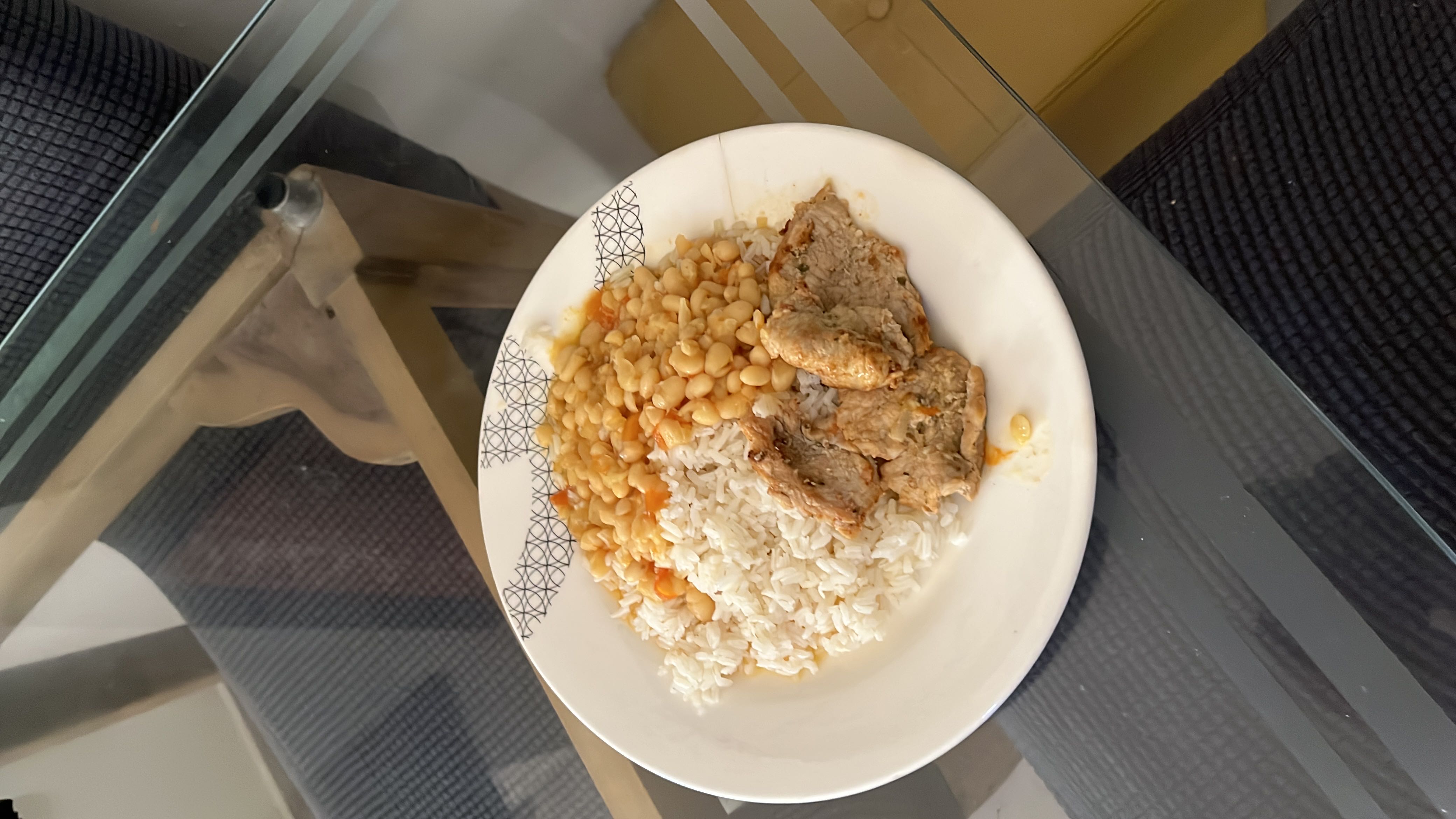 A balanced meal consisting of white rice, cooked white beans in a light sauce, and grilled meat, providing a good mix of protein, carbohydrates, and fats.