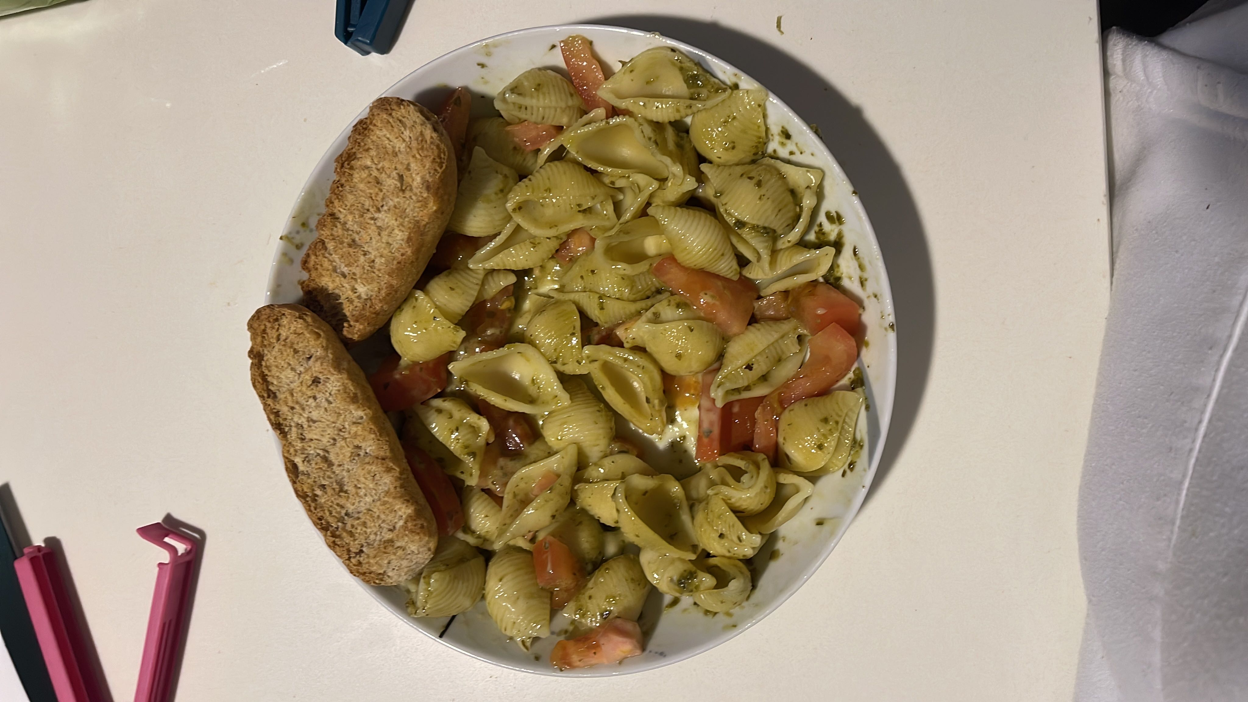 A pasta dish with pesto sauce, fresh tomatoes, and toasted bread, providing a balanced mix of carbohydrates, fats, and proteins.