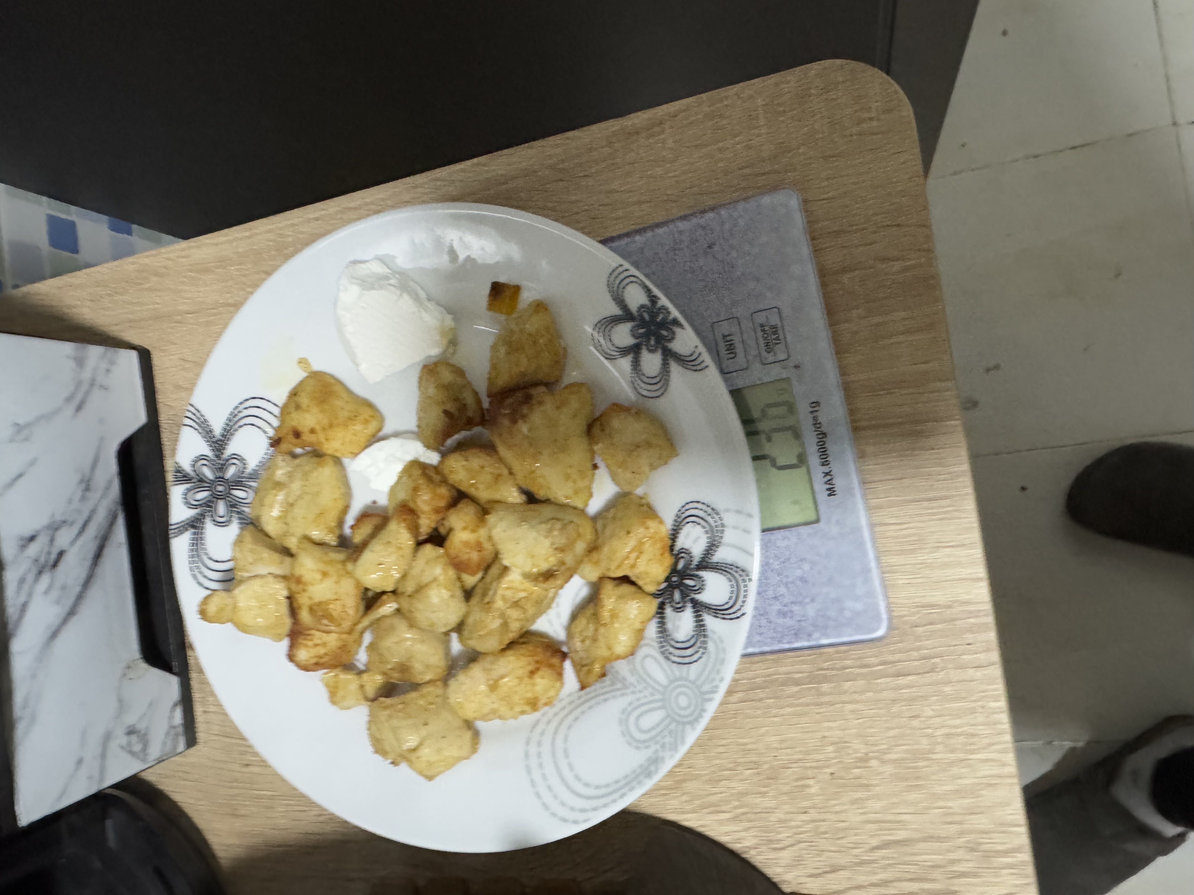 A plate of cooked chicken breast pieces with a side of cream cheese, placed on a digital scale displaying 235g.