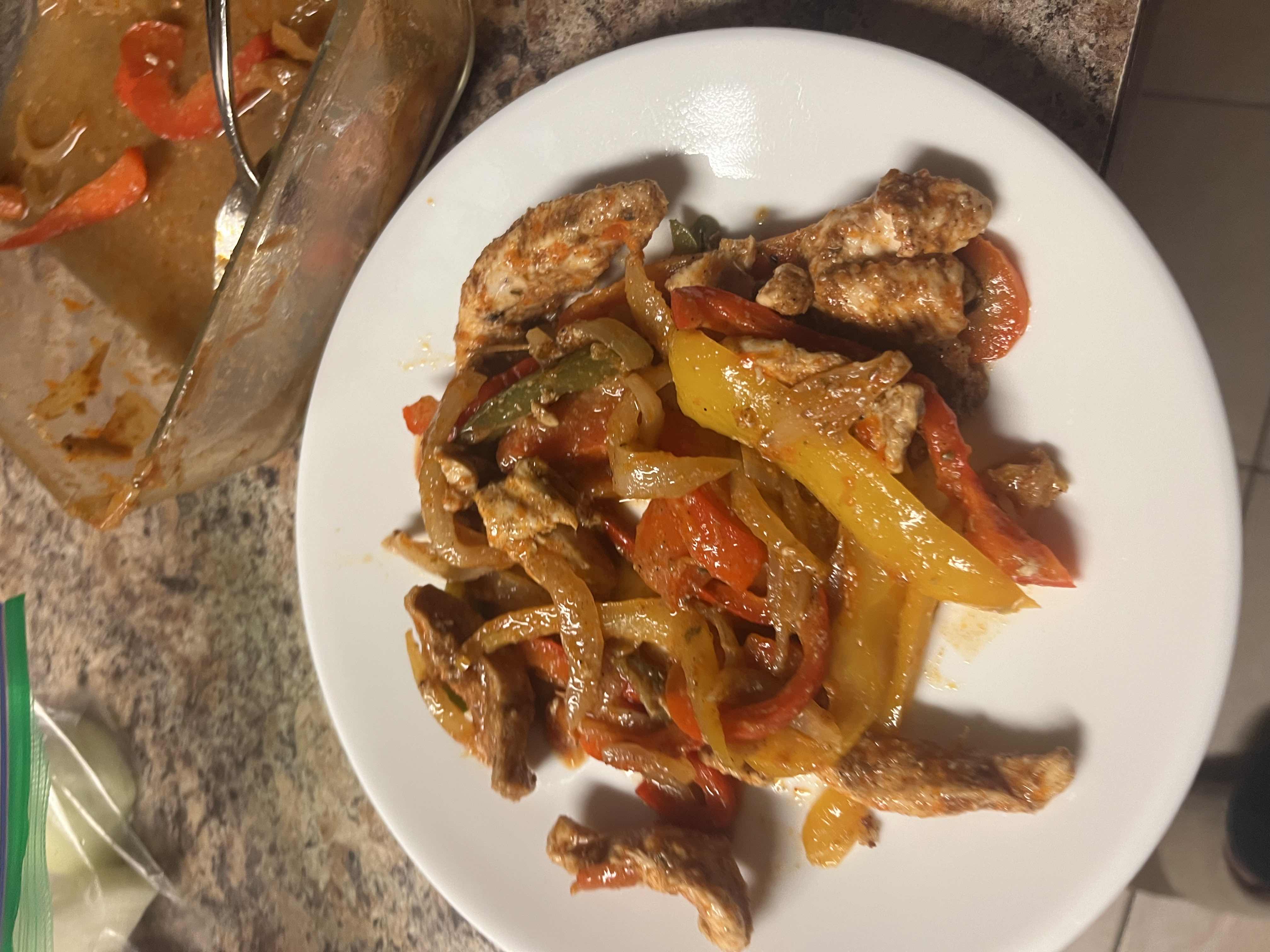 A healthy and flavorful dish consisting of seasoned chicken strips, bell peppers, and onions, cooked in a savory sauce.