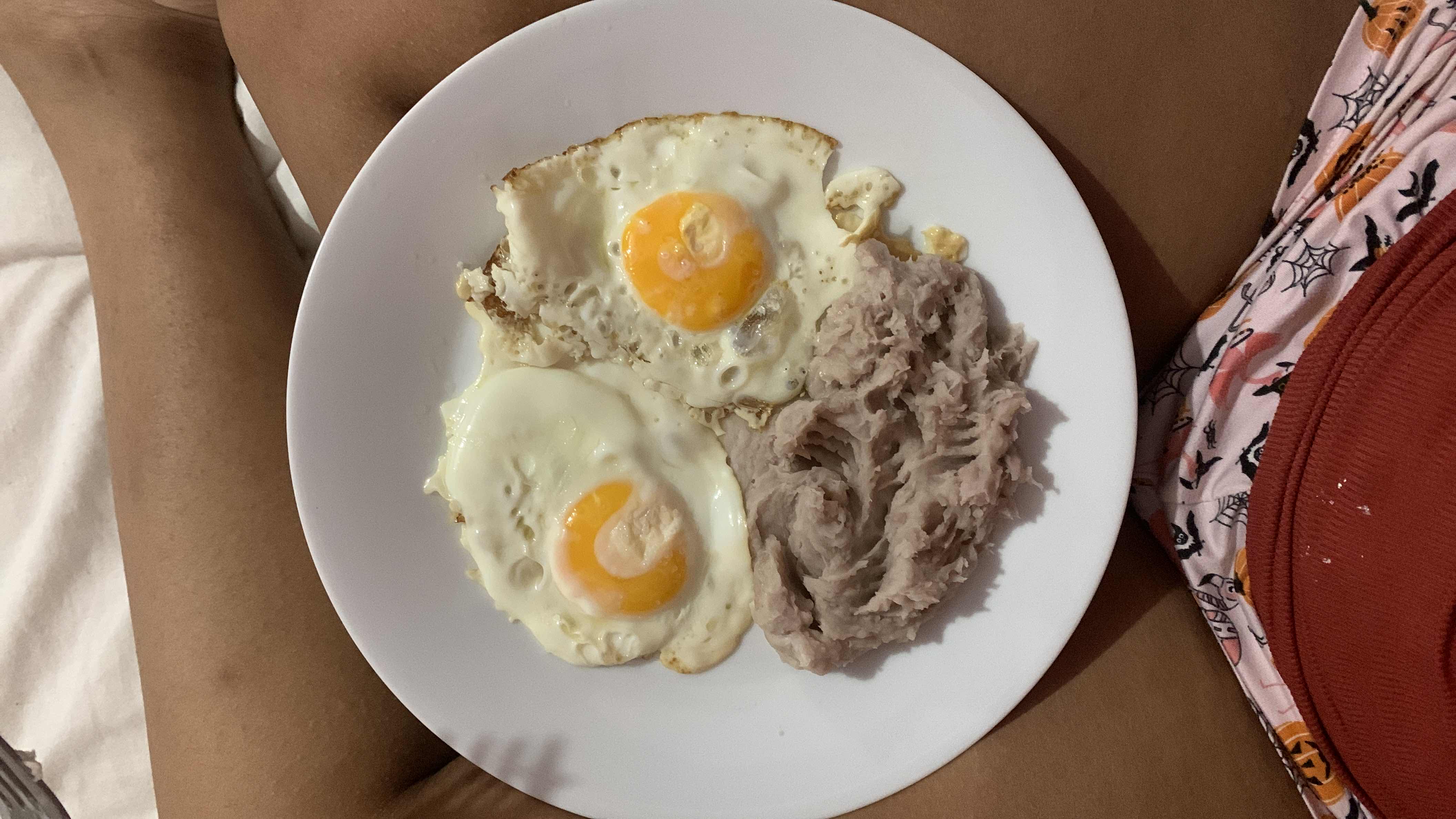 A plate containing two fried eggs and a serving of mashed taro, providing a balanced mix of protein, carbohydrates, and fats.
