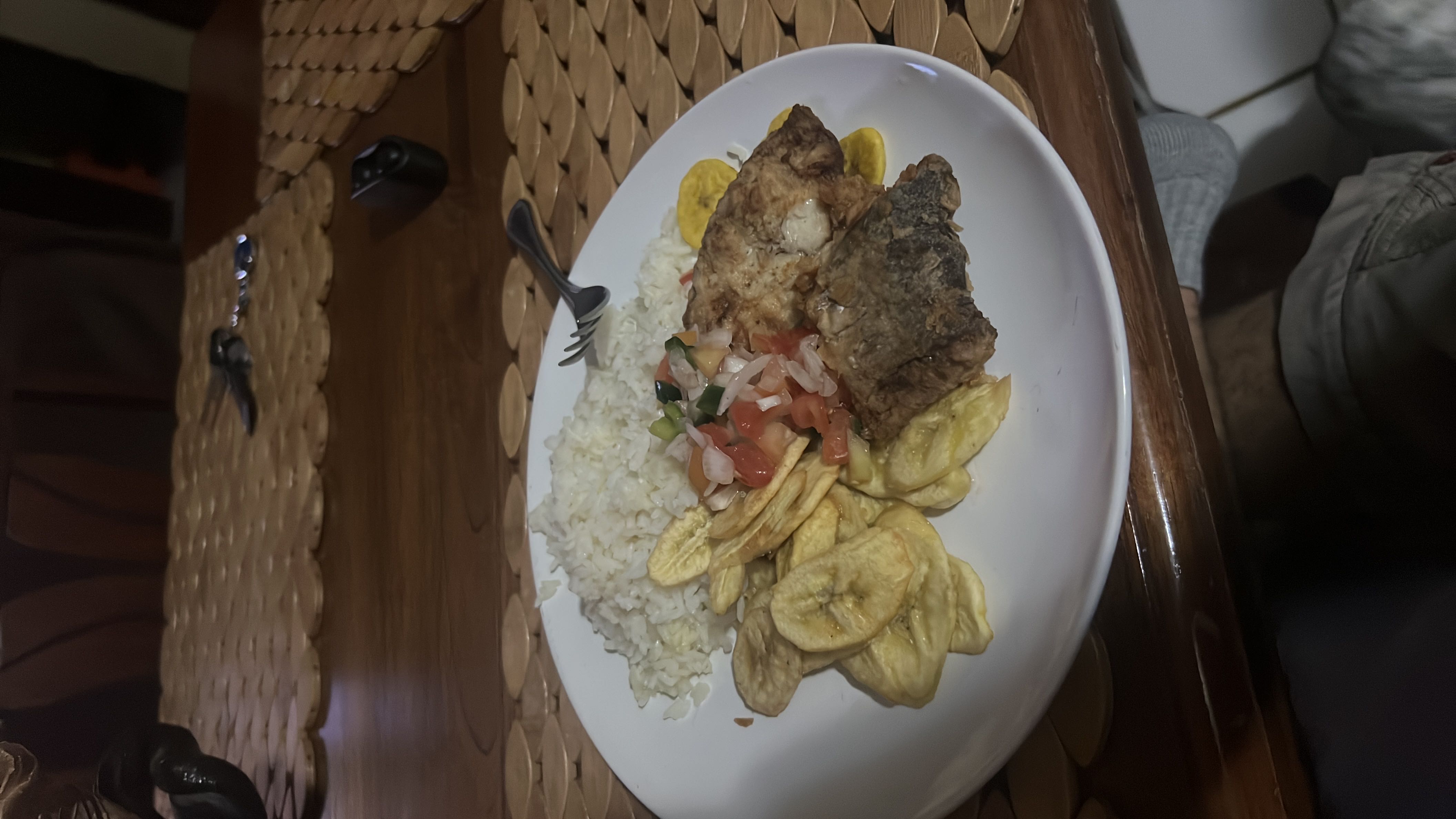 A balanced meal consisting of white rice, fried fish, fried plantains, and a fresh tomato-onion salad.
