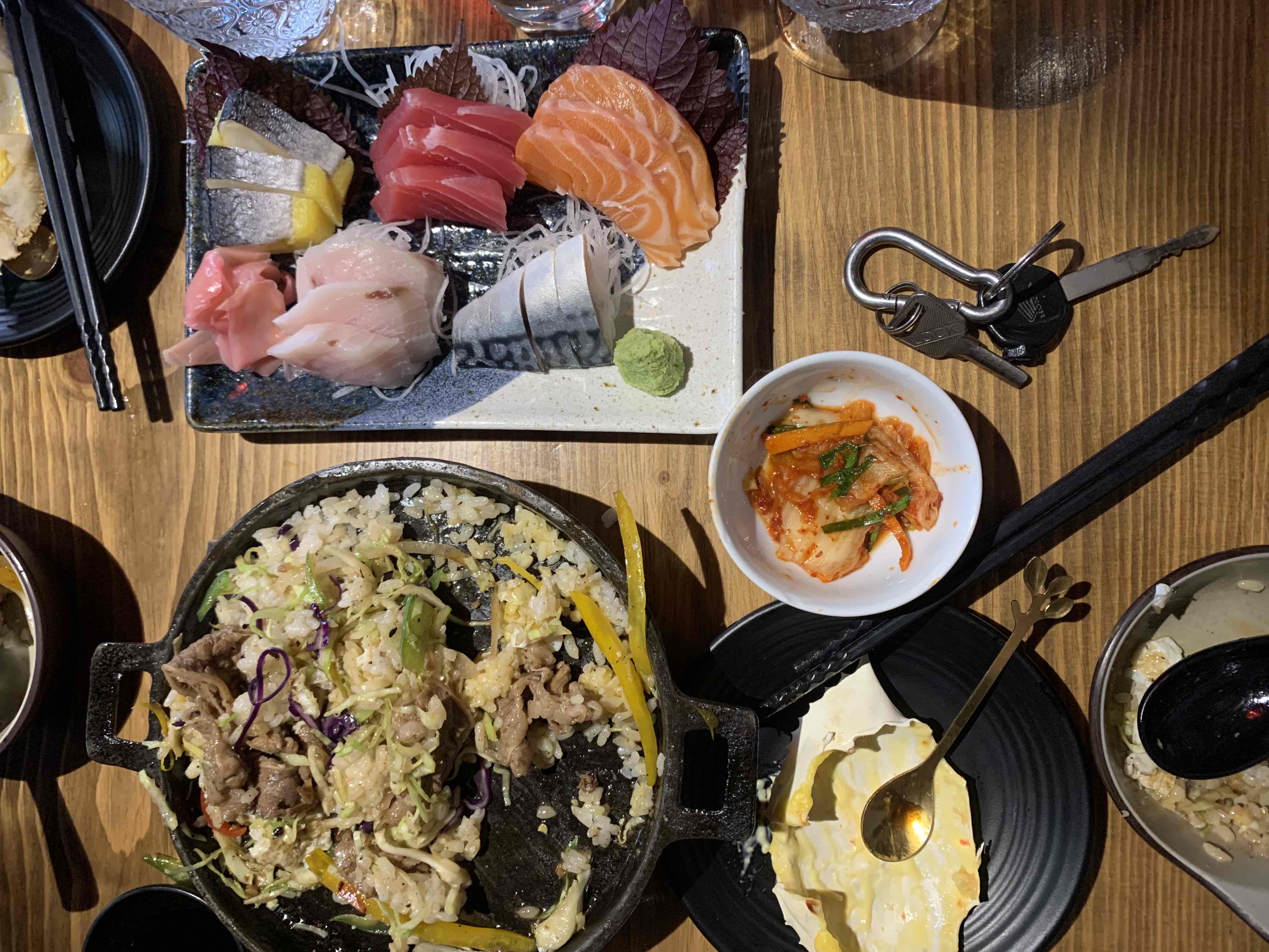 A balanced meal featuring fresh sashimi, stir-fried rice with beef and vegetables, and a cheese-based dish, providing a mix of protein, healthy fats, and carbohydrates.
