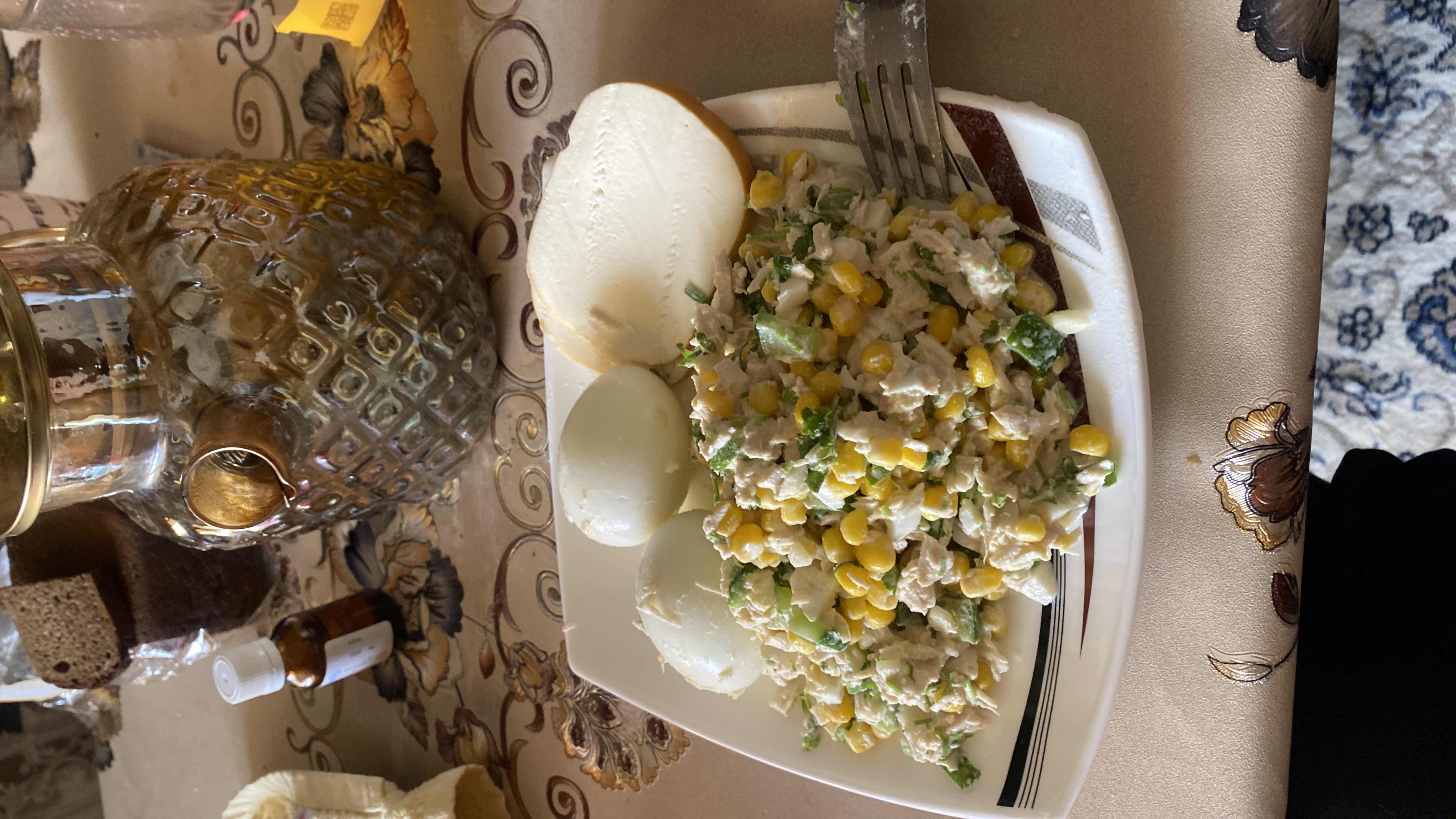 A protein-rich meal consisting of boiled eggs, chicken salad with corn and mayonnaise, and a slice of cheese.