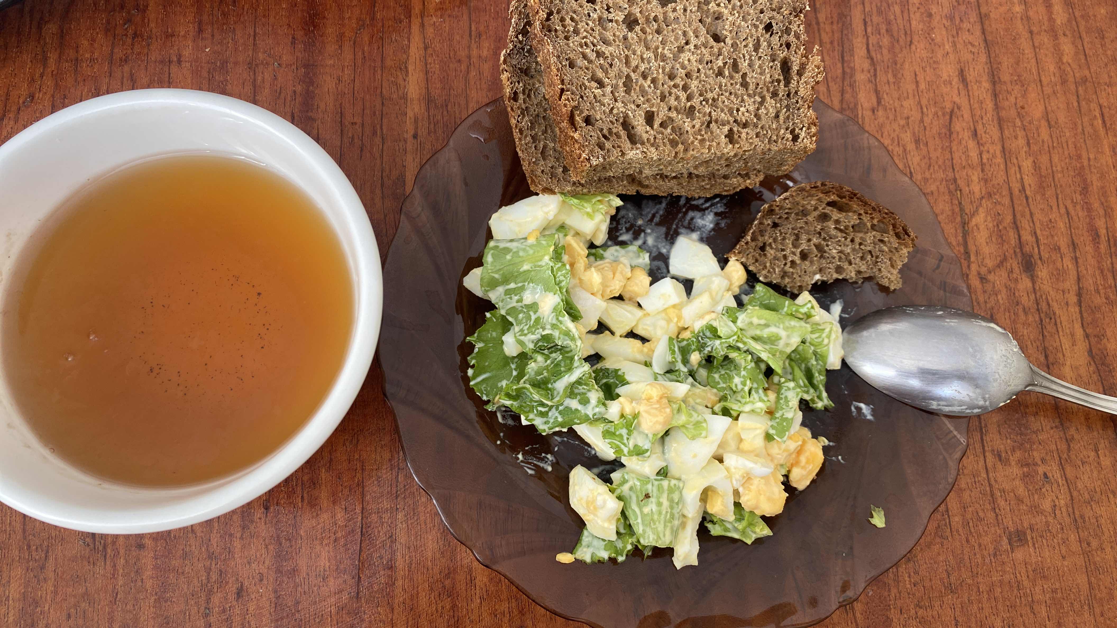 A balanced meal consisting of a lettuce and boiled egg salad with mayonnaise, rye bread, and a cup of tea.