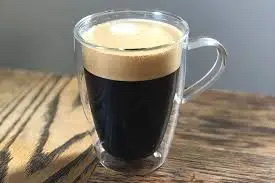 A cup of black coffee with a creamy froth layer, low in calories and free of fats and carbs.