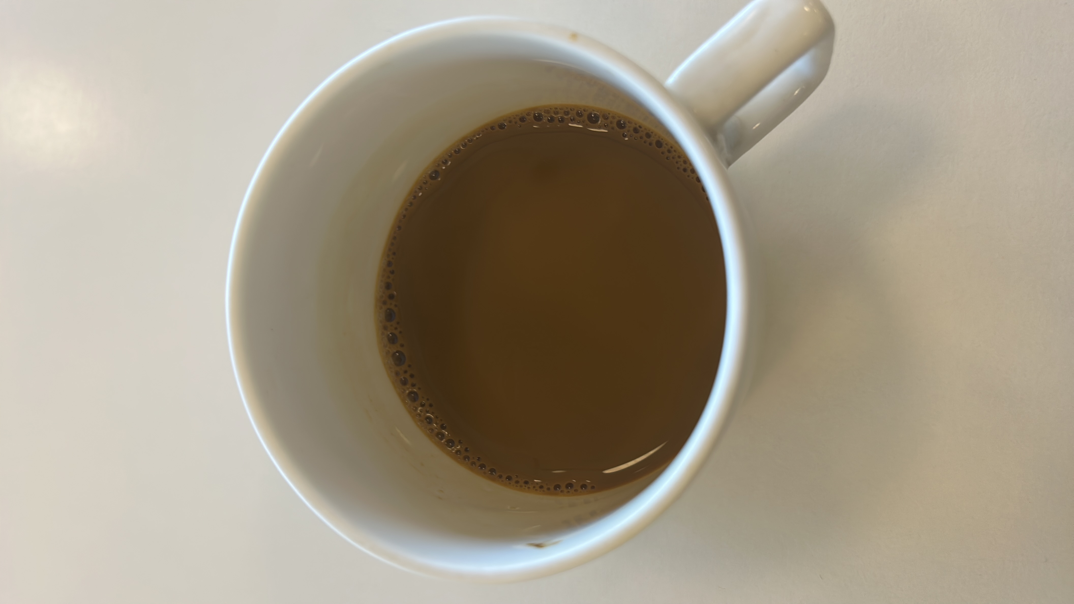 A cup of coffee with milk, providing a low-calorie beverage with minimal fats and carbohydrates.