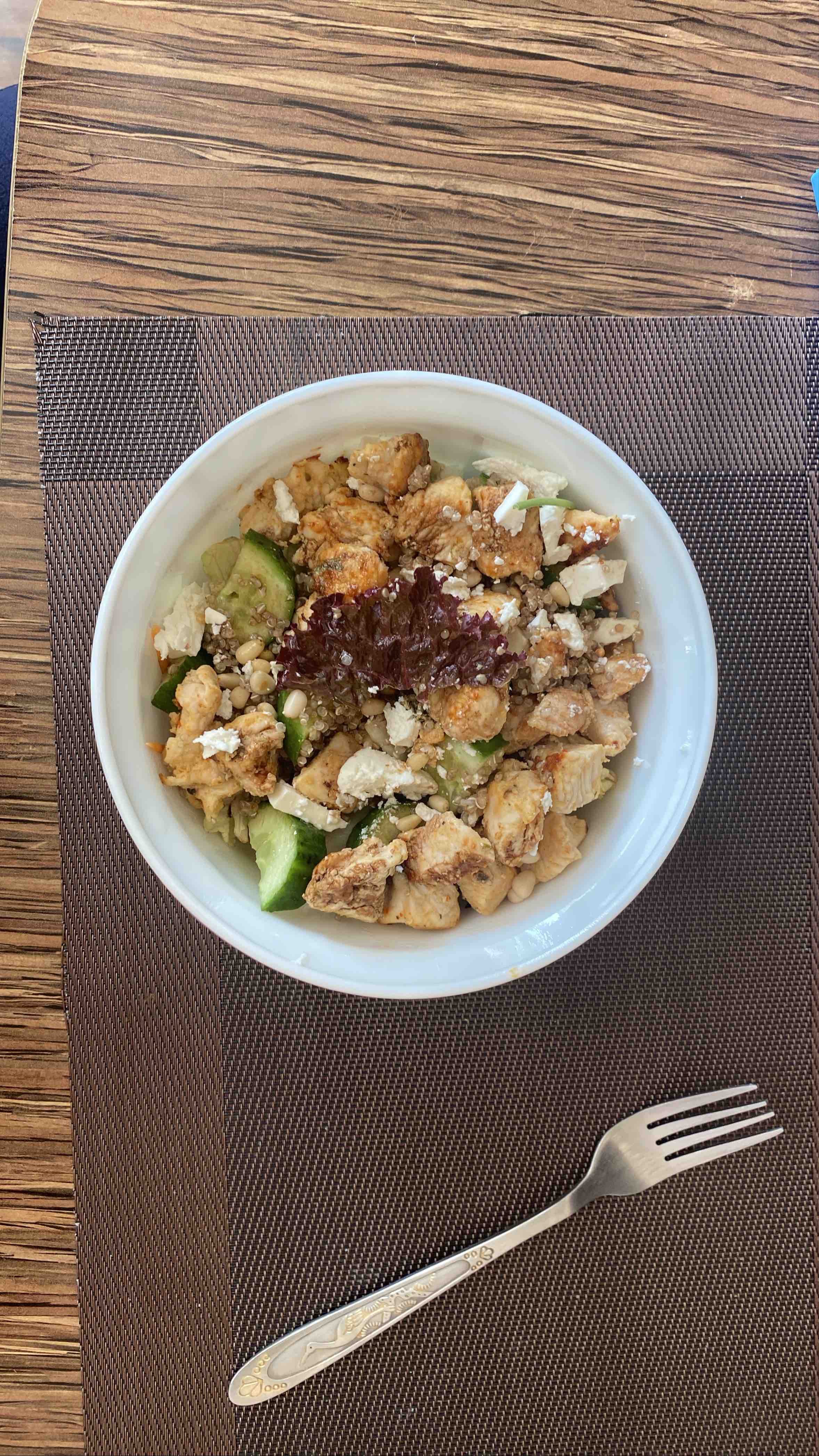 A high-protein quinoa bowl with grilled chicken, fresh cucumbers, feta cheese, and pine nuts, offering a balanced mix of macronutrients.