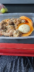 A balanced meal containing seasoned meat, a boiled egg, and slices of papaya, providing a good mix of protein, carbohydrates, and healthy fats.