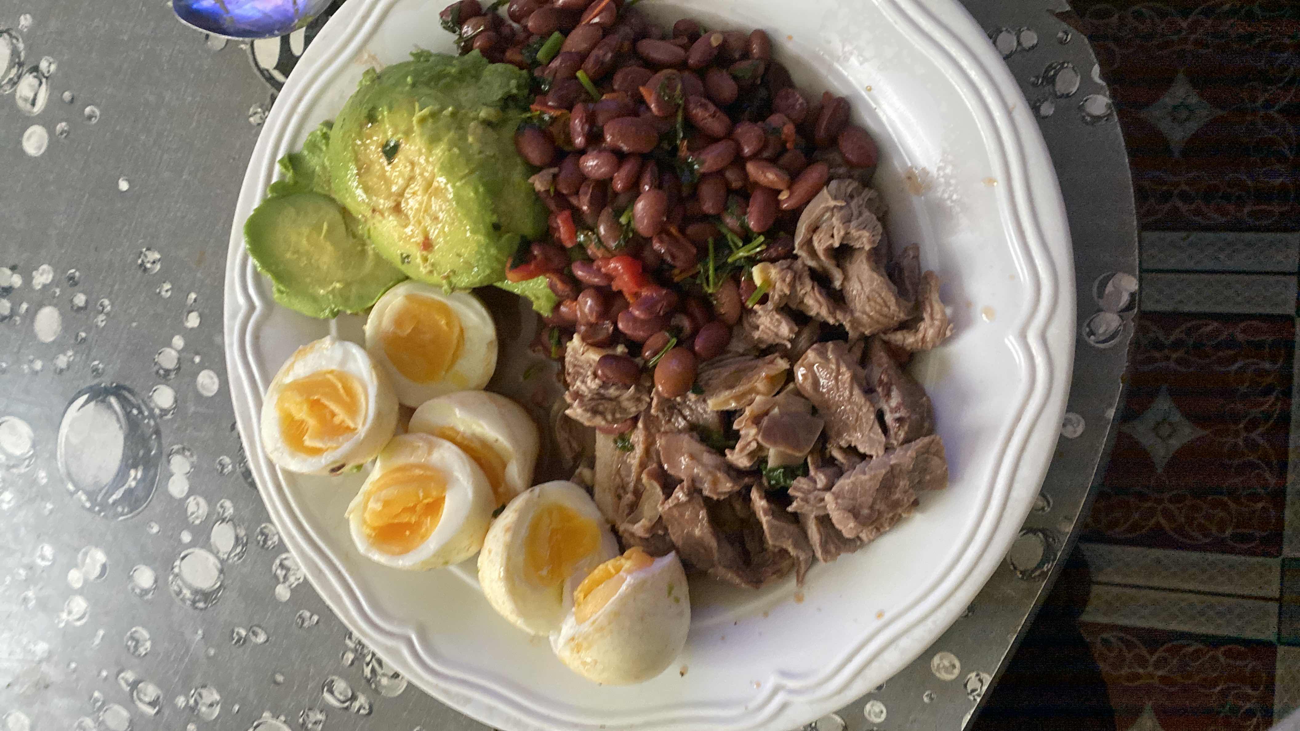 A high-protein meal consisting of boiled eggs, avocado, red beans, and boiled beef, providing a balanced mix of macronutrients.