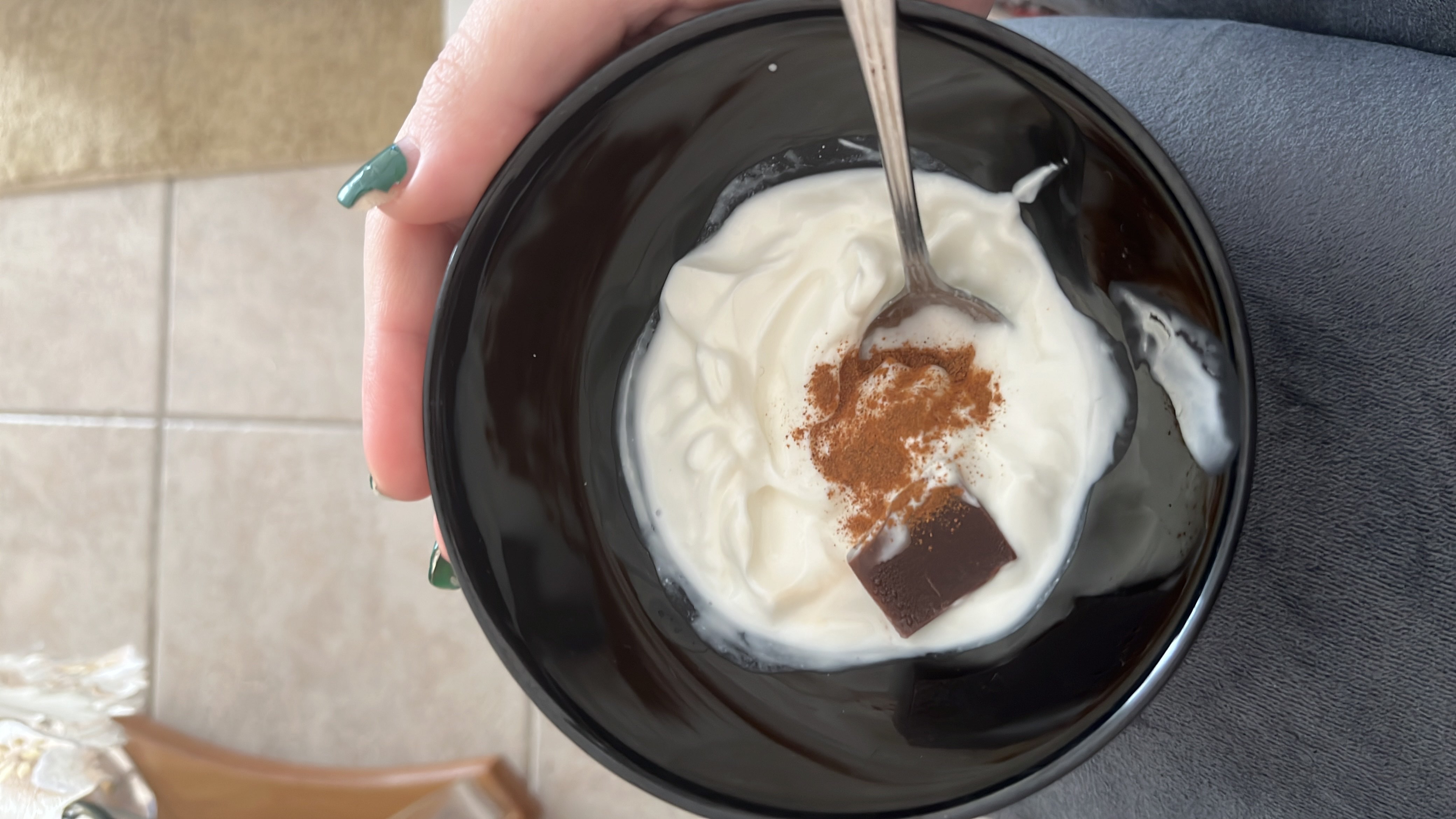 A bowl of Greek yogurt topped with a piece of dark chocolate and a sprinkle of cinnamon, providing a balanced mix of protein, healthy fats, and carbohydrates.