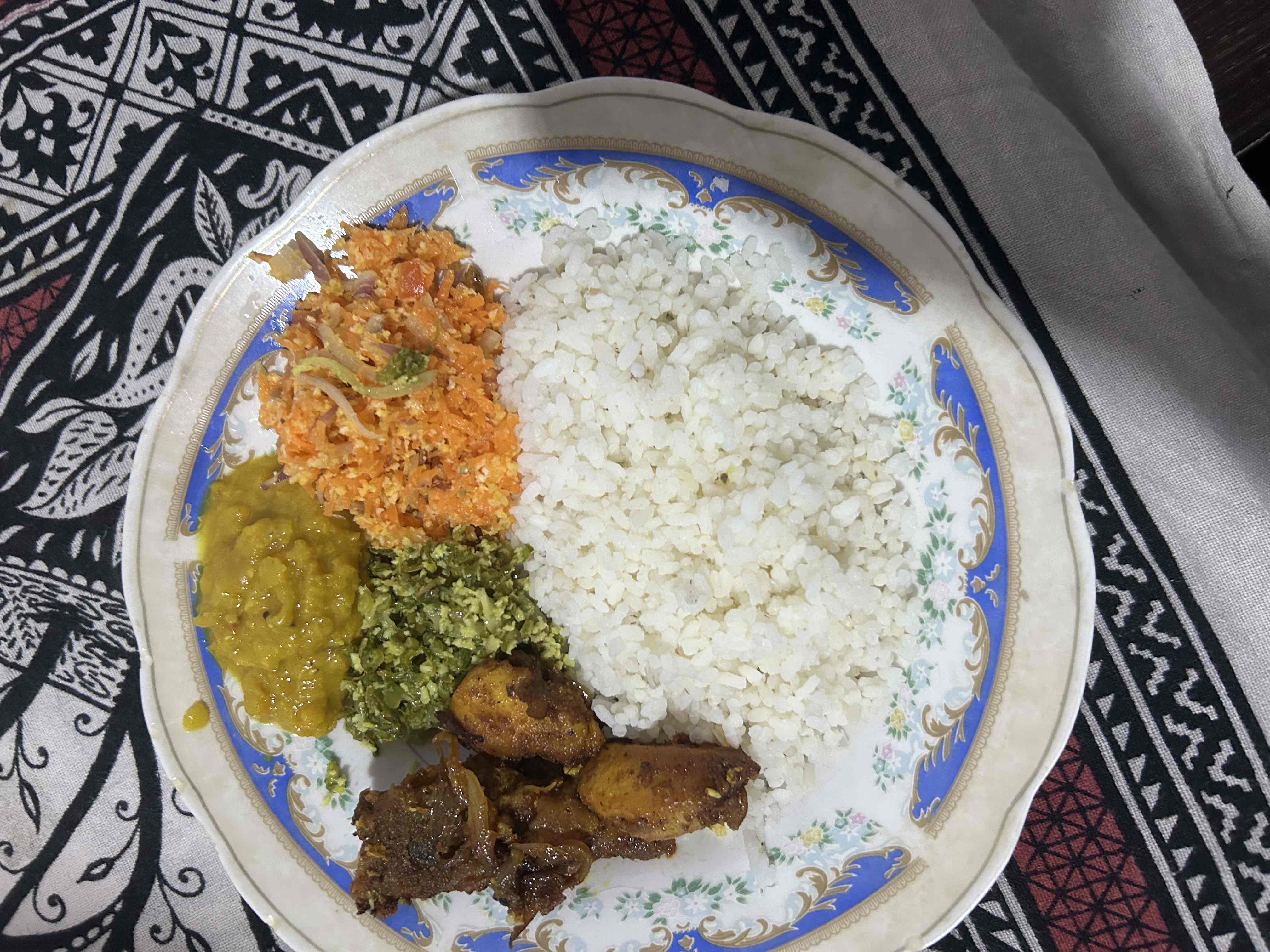 A balanced meal consisting of rice, lentil curry, chicken curry, and vegetable sides, providing a good mix of carbohydrates, proteins, and fats.