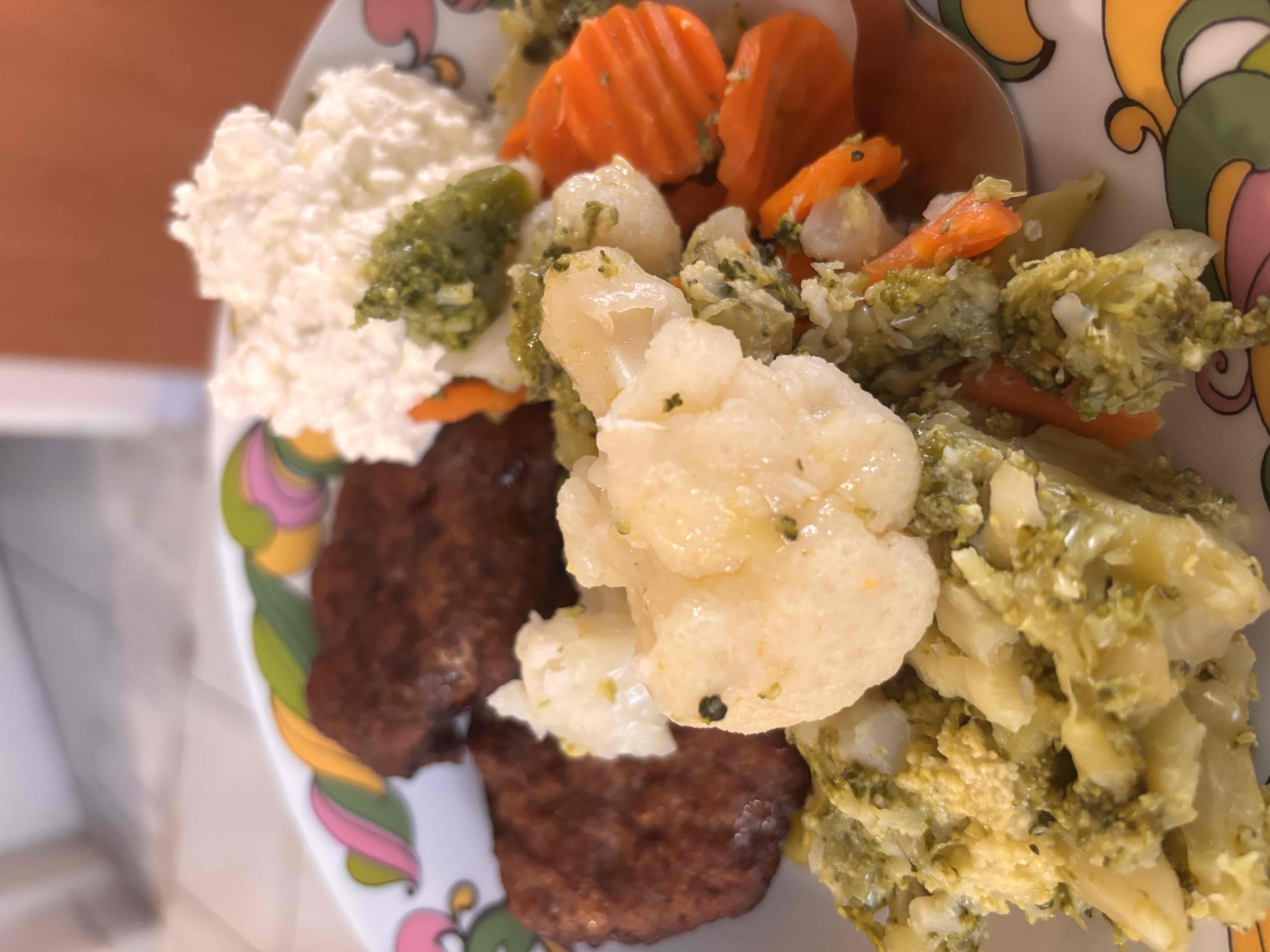 A balanced meal consisting of ground beef patties, steamed vegetables including broccoli, cauliflower, and carrots, and a serving of cottage cheese.