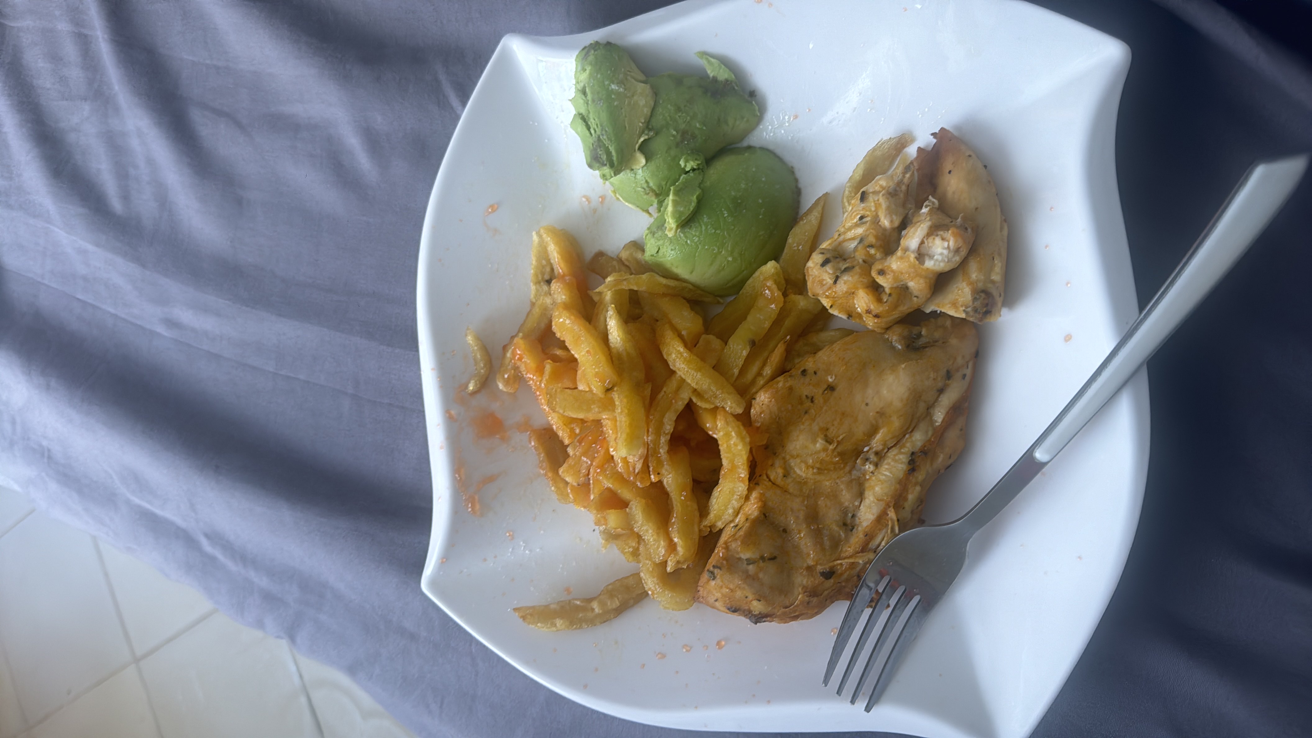 A balanced meal consisting of grilled chicken, French fries with sauce, and fresh avocado, providing a mix of protein, healthy fats, and carbohydrates.