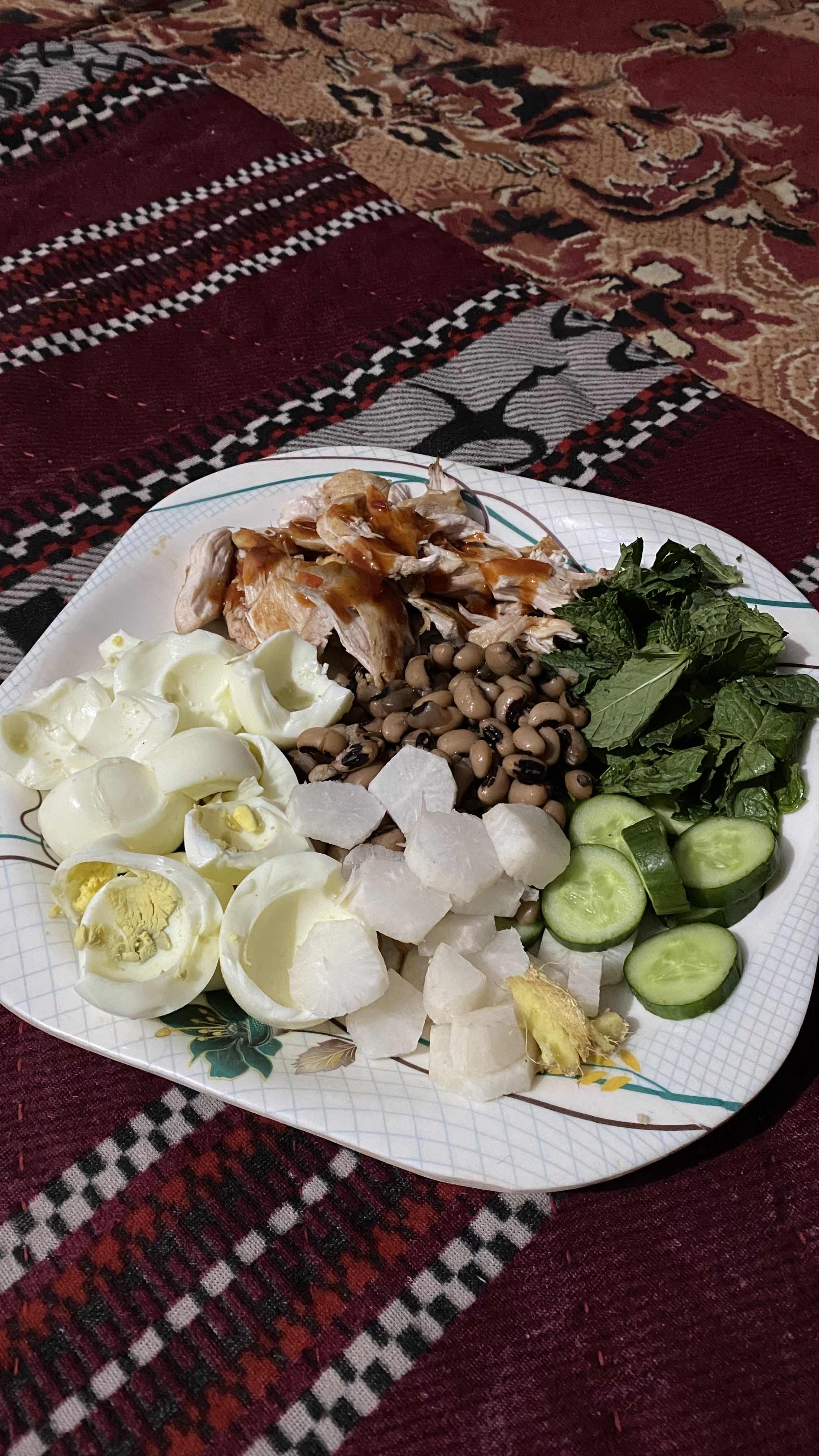 A high-protein meal consisting of boiled eggs, grilled chicken, black-eyed peas, cucumber, radish, and fresh mint leaves, offering a balanced mix of protein, healthy fats, and fiber.