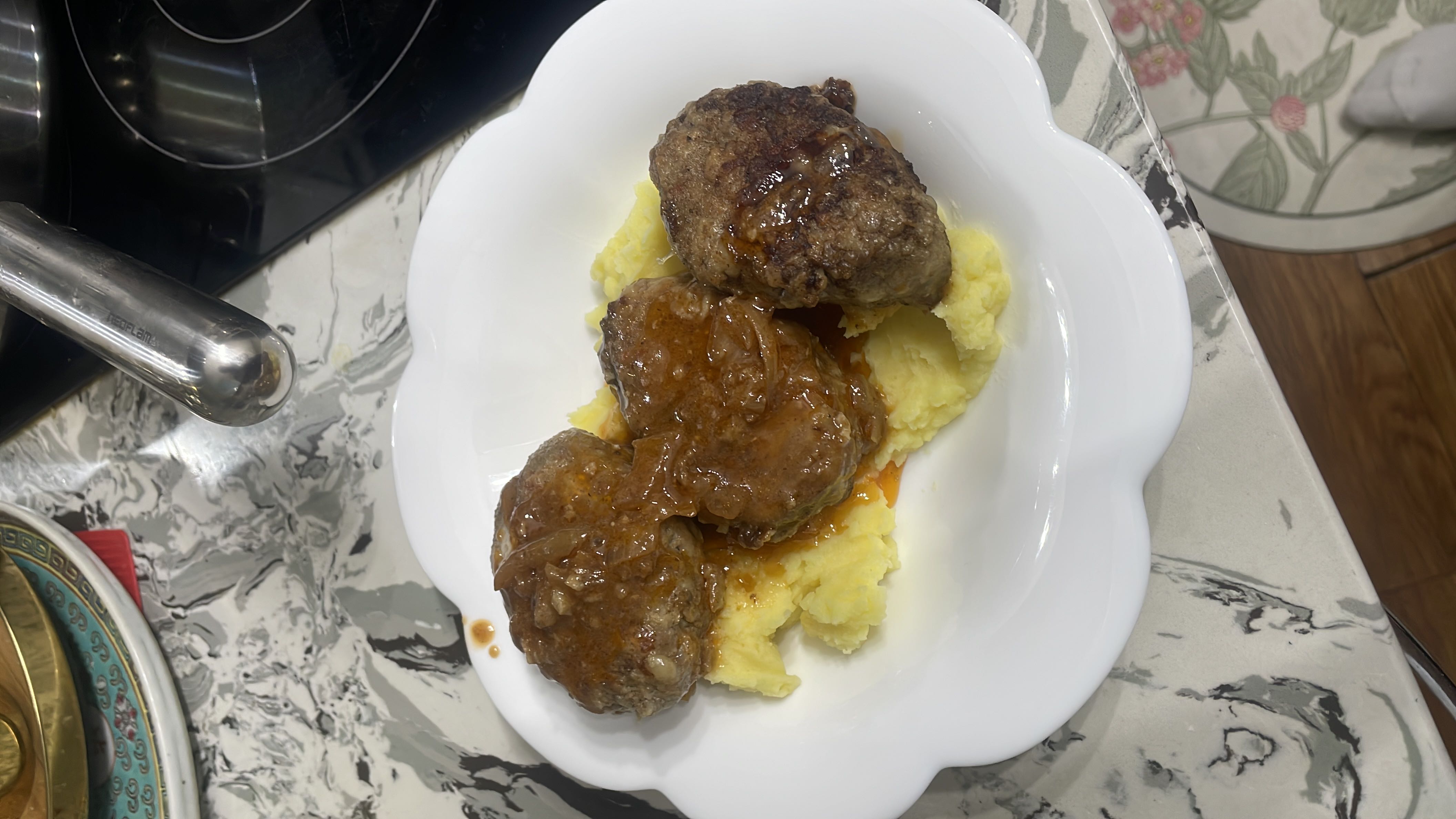 A hearty dish consisting of pan-seared beef patties served over creamy mashed potatoes, topped with a rich onion gravy.