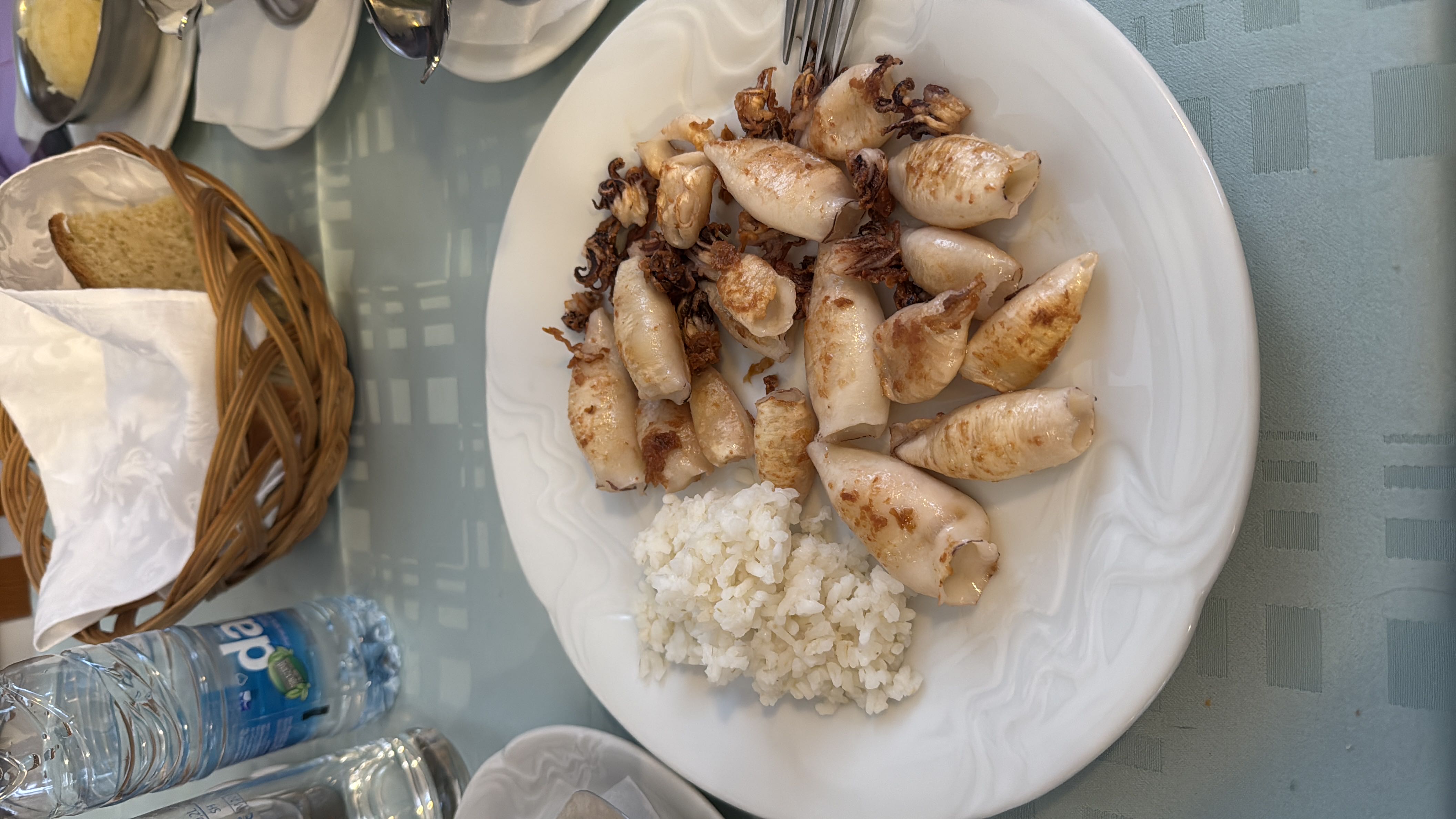 A plate of grilled squid served with a side of white rice, offering a balanced meal with high protein and moderate carbs.