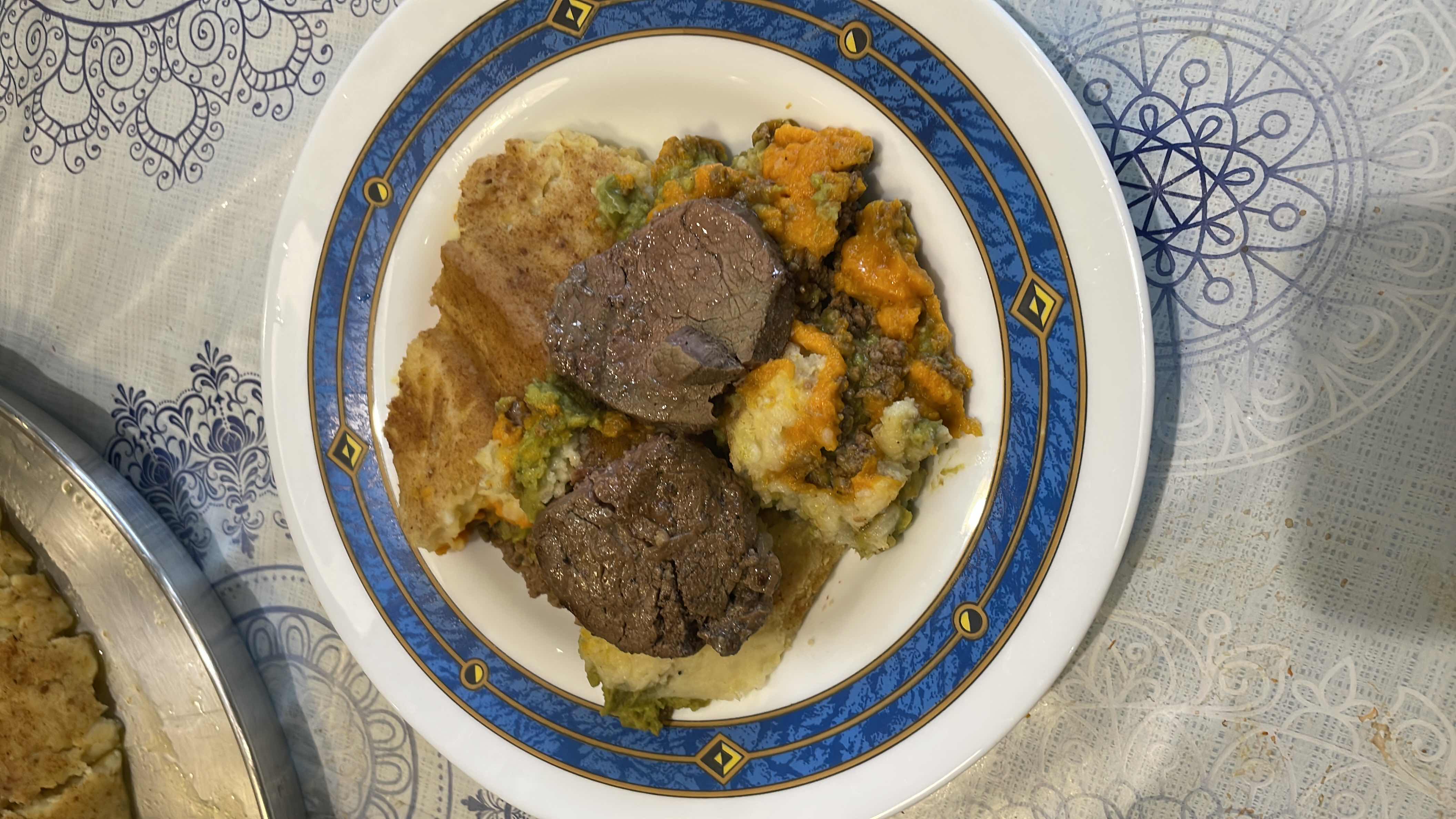 A hearty meal consisting of beef, mashed potatoes, cheese, and vegetables, providing a balanced mix of protein, carbs, and fats.