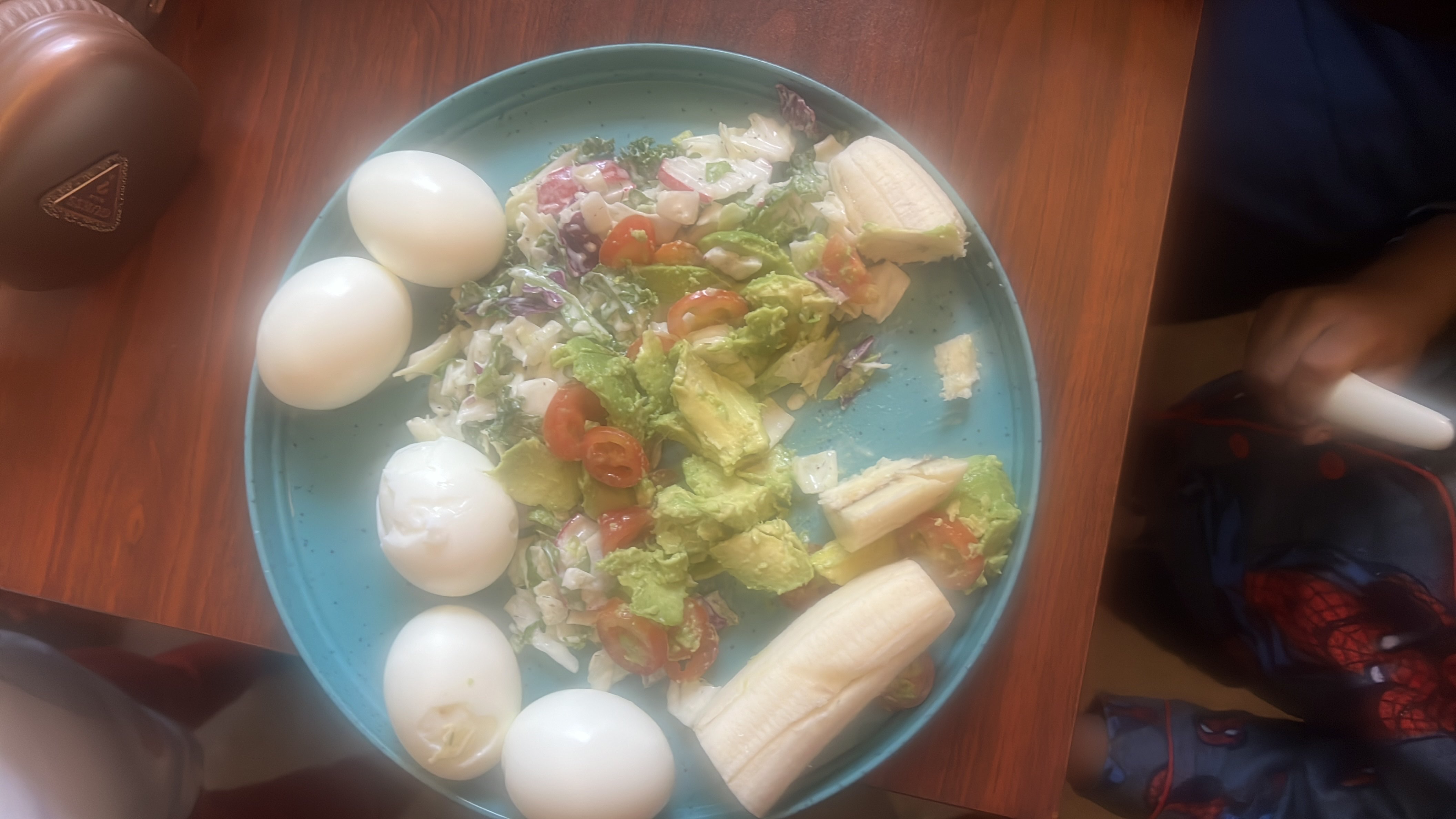 A balanced meal consisting of boiled eggs, a fresh salad with avocado and tomatoes, and a banana, providing a mix of protein, healthy fats, and carbohydrates.