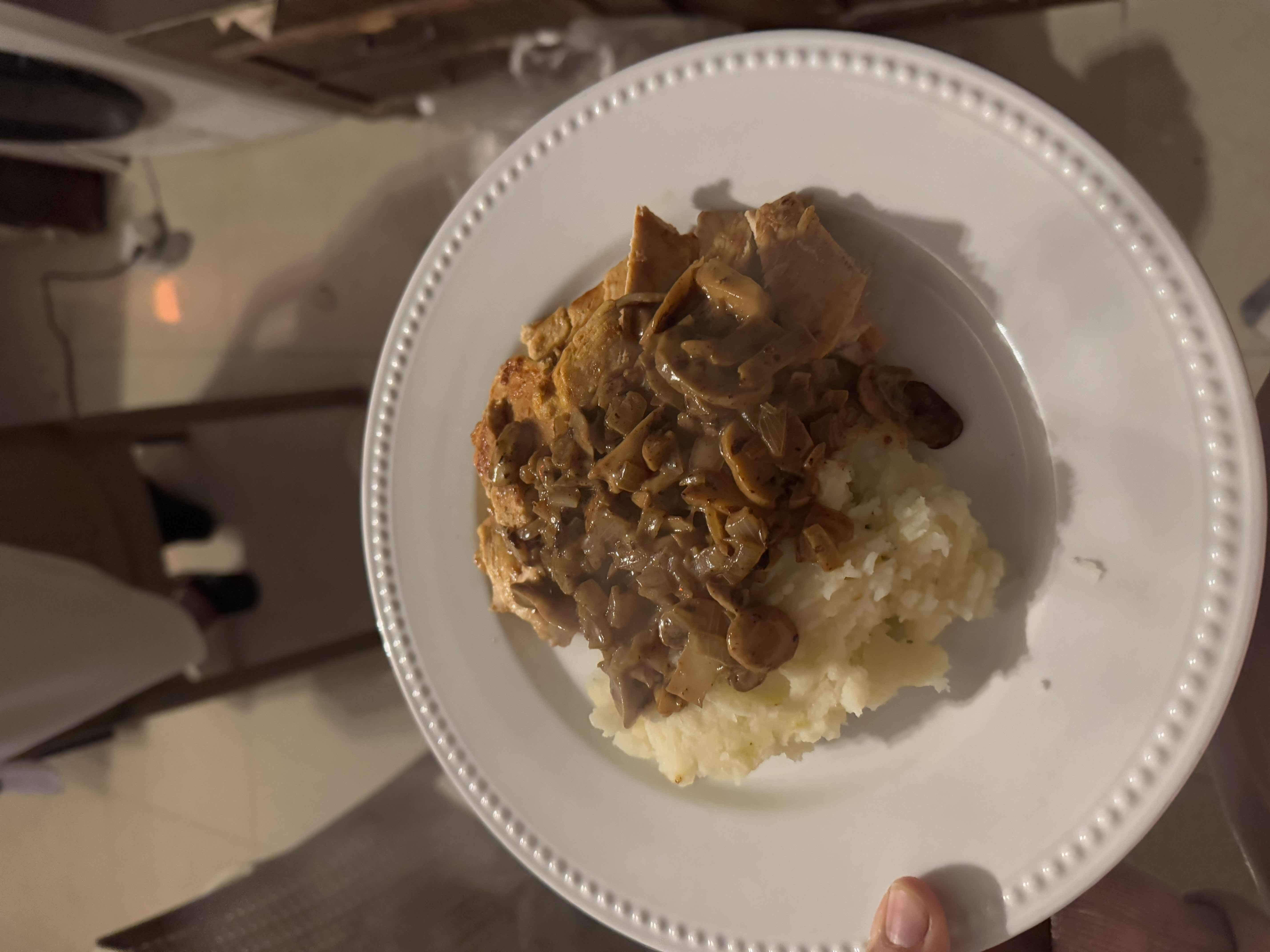 A plate of chicken breast with mushroom sauce served over mashed potatoes, providing a balanced mix of protein, carbohydrates, and fats.