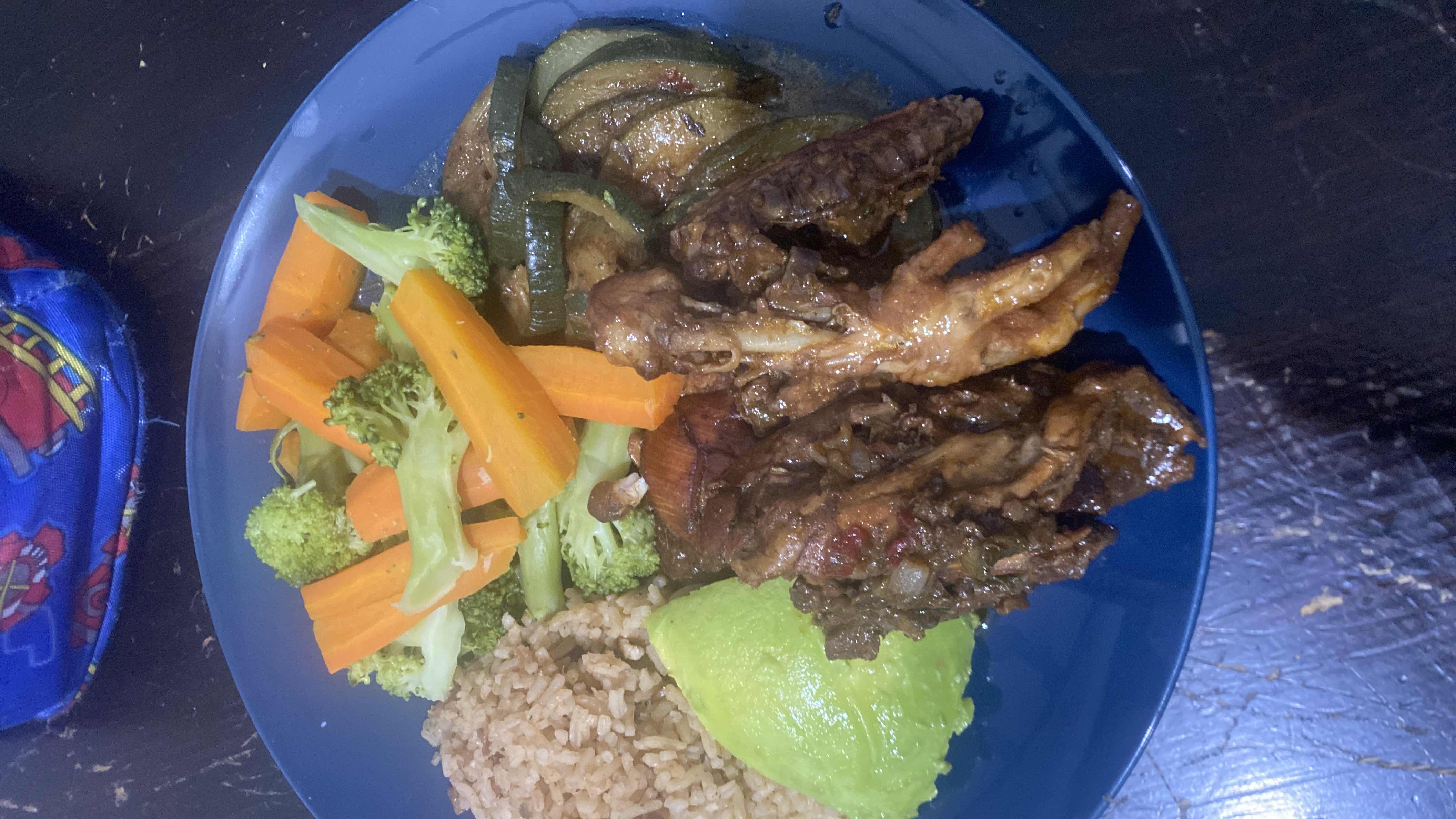 A balanced meal consisting of stewed chicken, brown rice, and a variety of vegetables including carrots, broccoli, zucchini, and avocado.