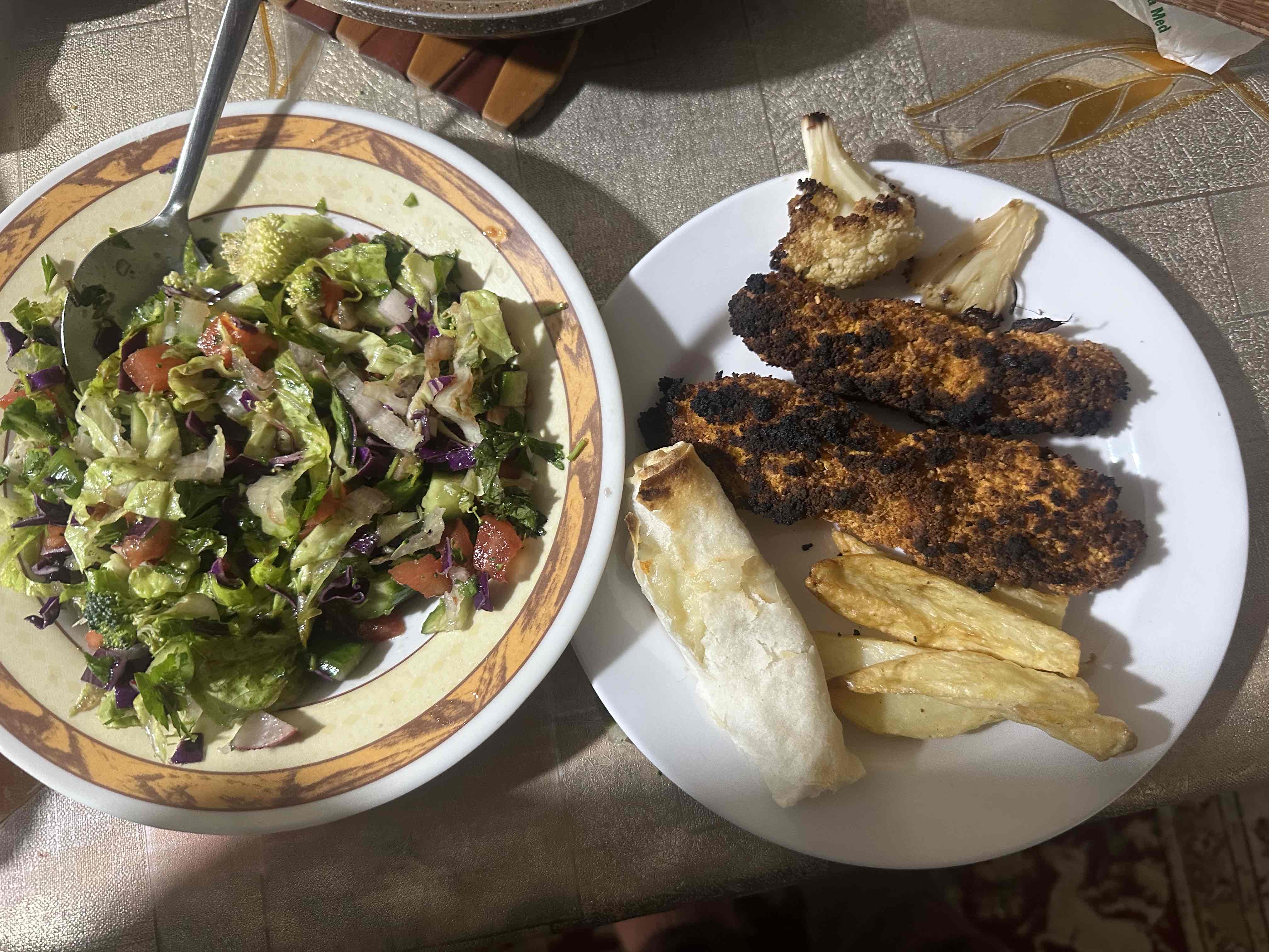 A balanced meal consisting of grilled chicken, fresh salad, potato wedges, and a bread roll, providing a mix of protein, carbohydrates, and healthy fats.