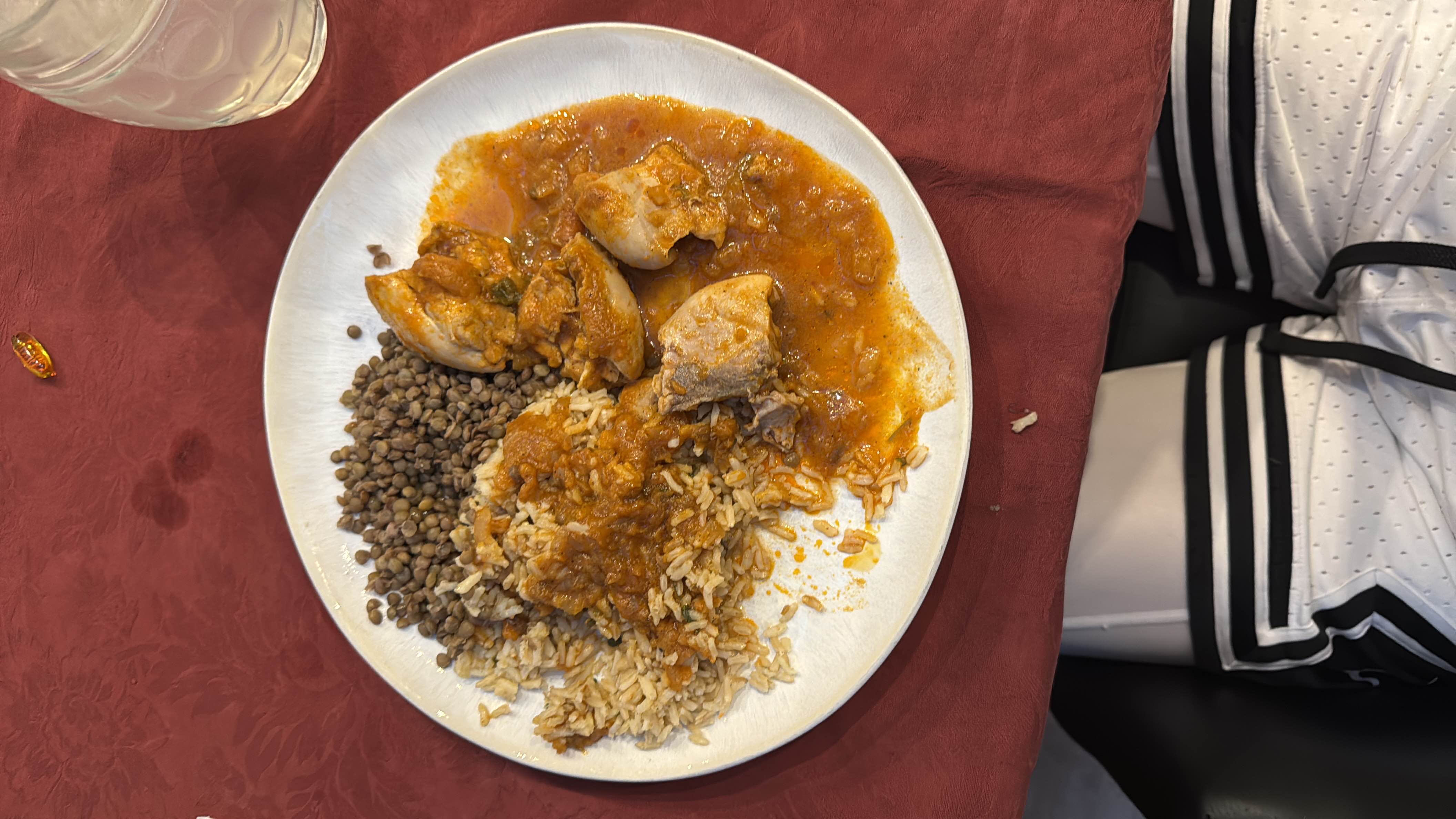 A balanced meal consisting of chicken in tomato-based sauce, rice, and lentils, providing a good mix of protein, carbohydrates, and fats.