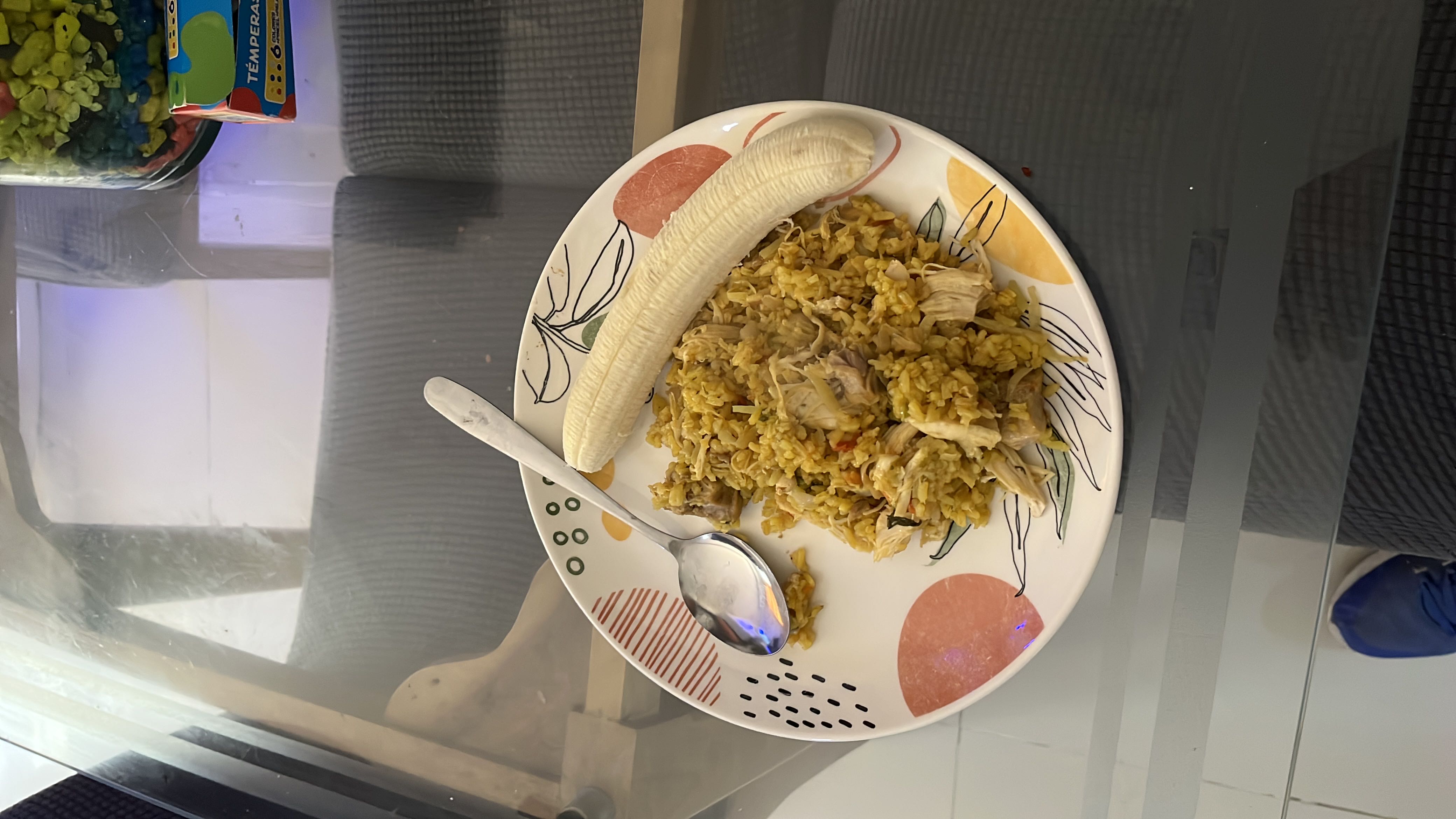 A plate of seasoned rice with shredded chicken and a banana, providing a balanced mix of protein, carbohydrates, and fats.
