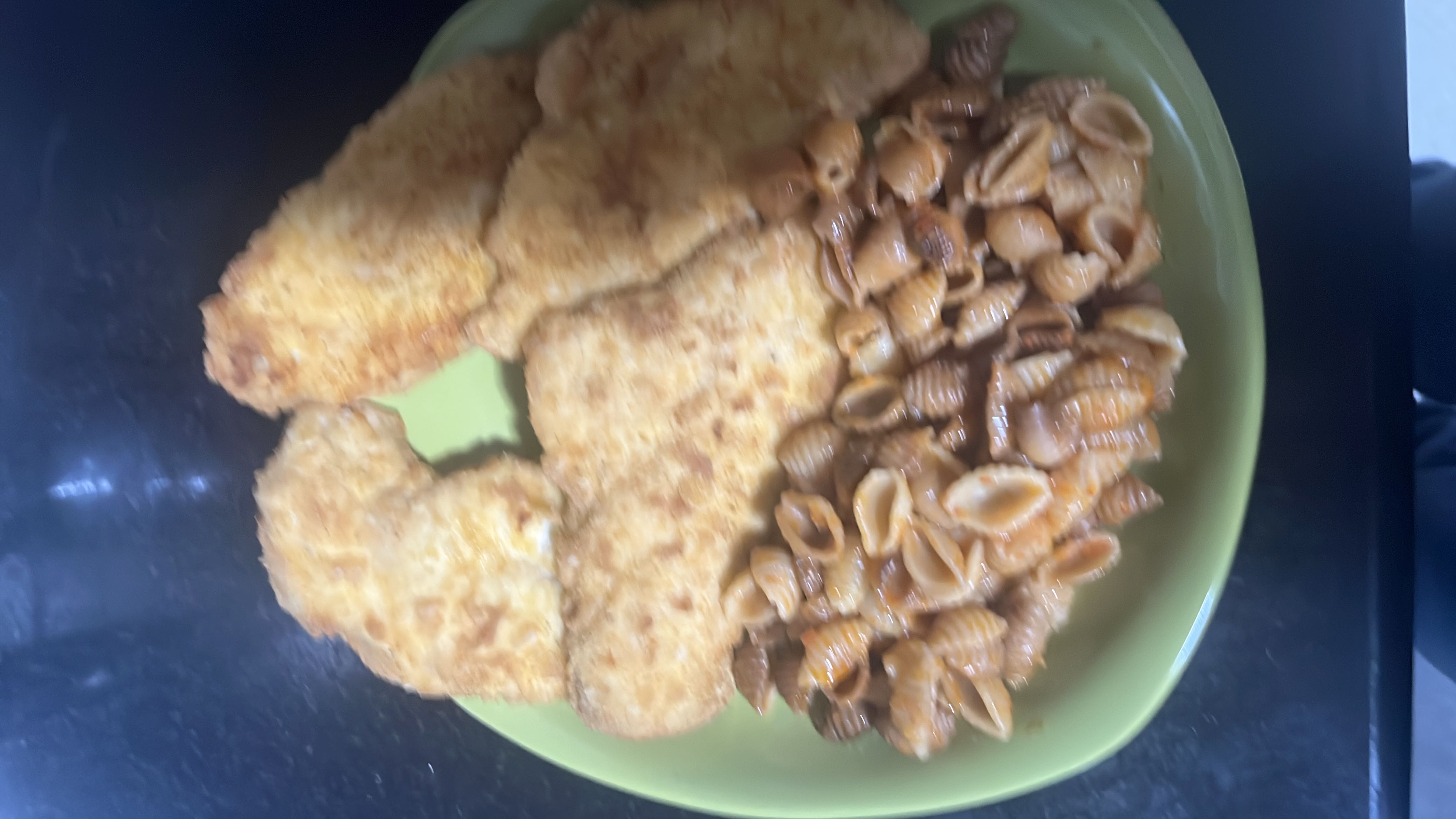 A meal consisting of breaded and fried chicken fillets served with shell pasta coated in a sauce.