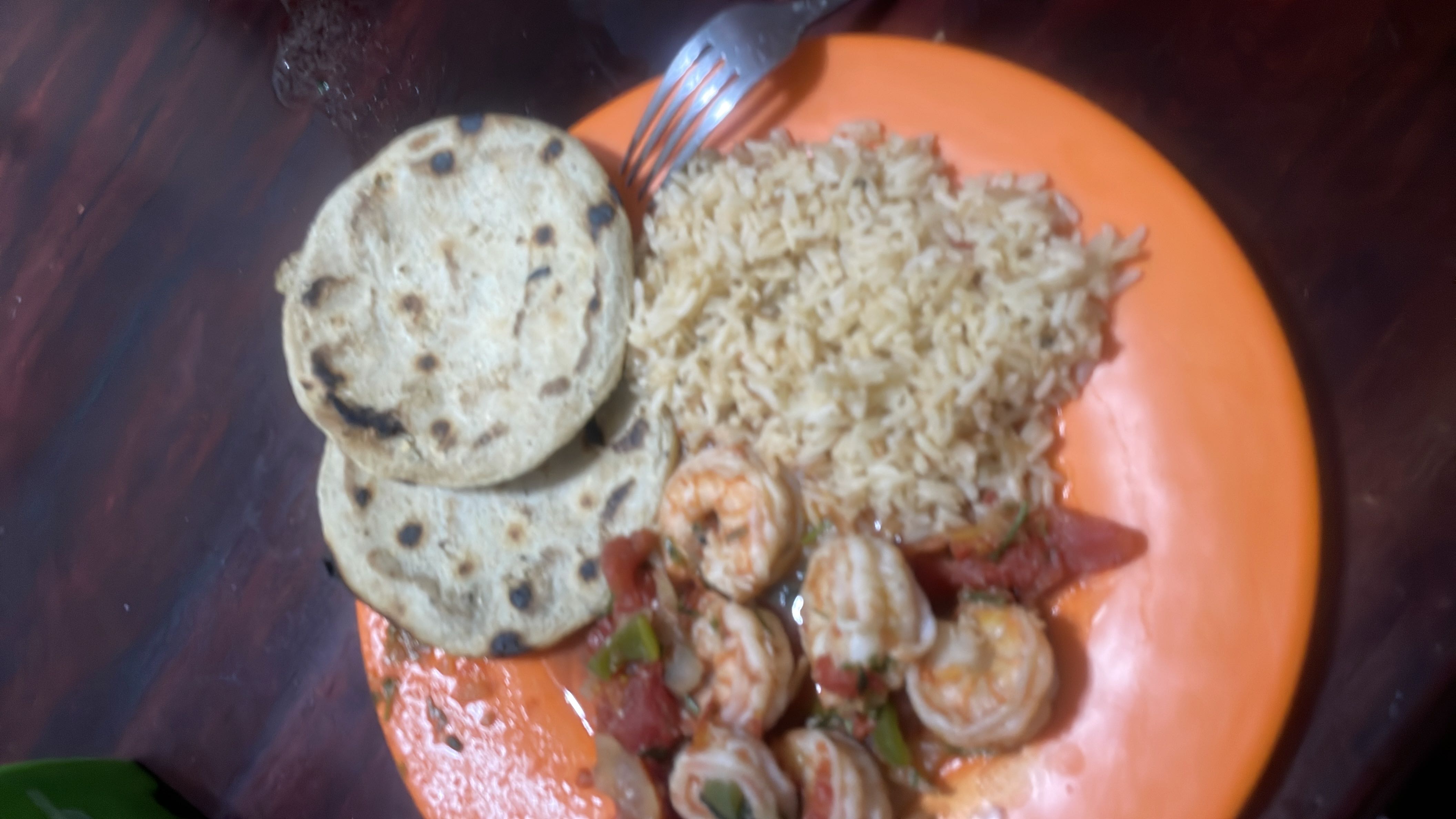 A balanced meal consisting of shrimp in a tomato-based sauce, rice, and corn tortillas, providing a good mix of protein, carbohydrates, and fats.