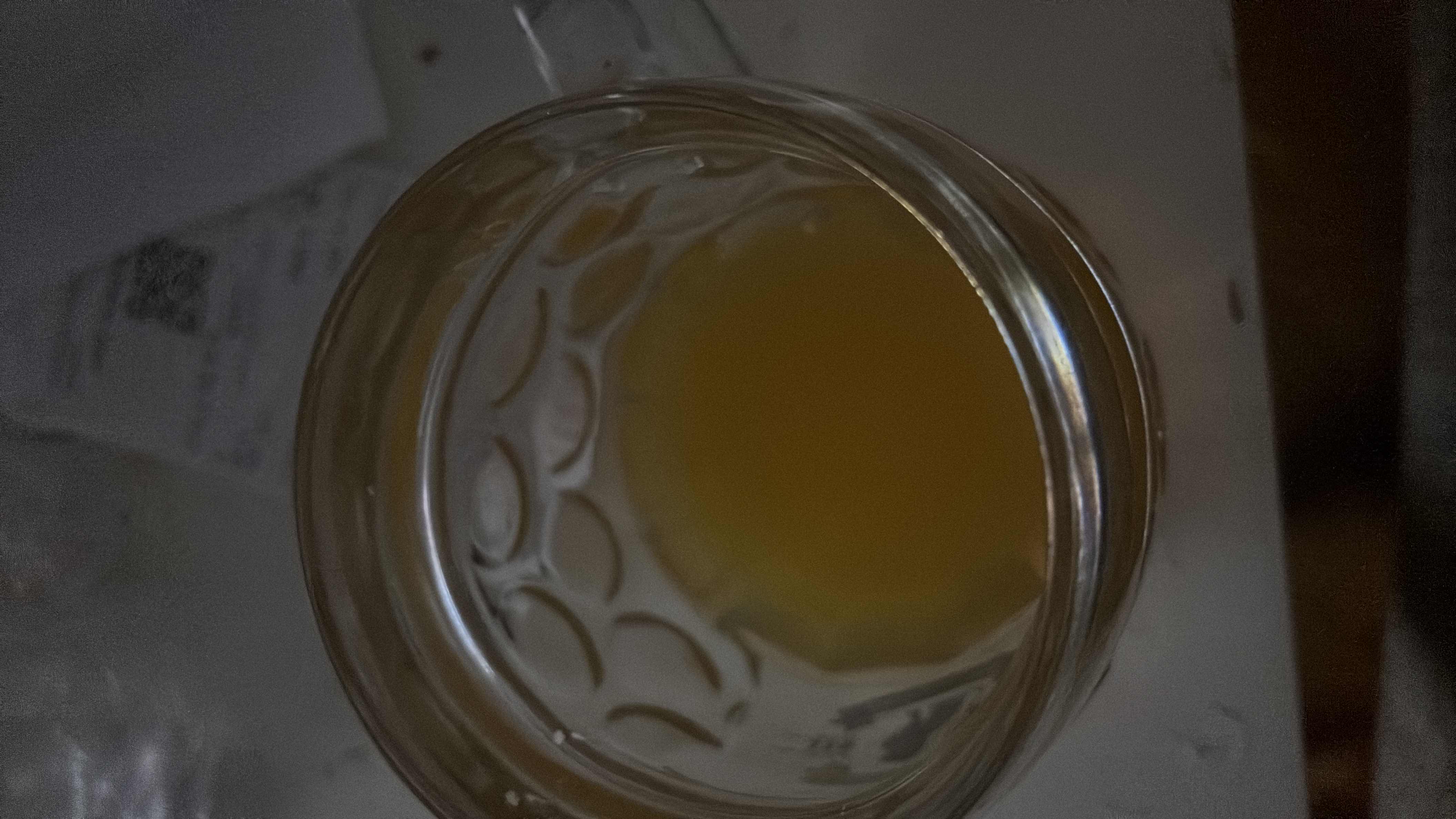 A glass of juice with a light yellowish color, likely fruit-based, containing moderate carbohydrates and minimal fats or proteins.