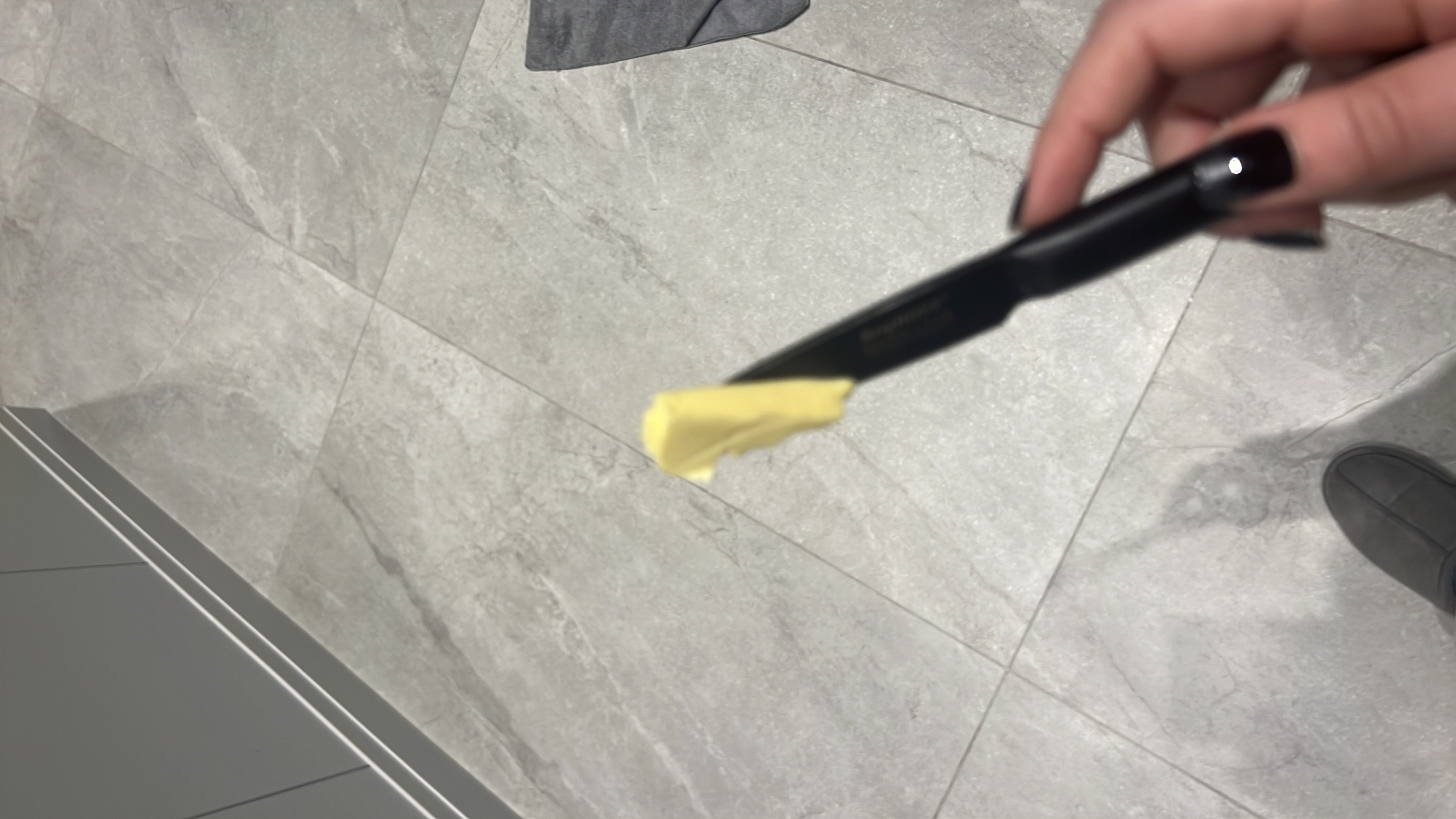 A small portion of butter on a knife, high in fats and calories with no protein or carbs.